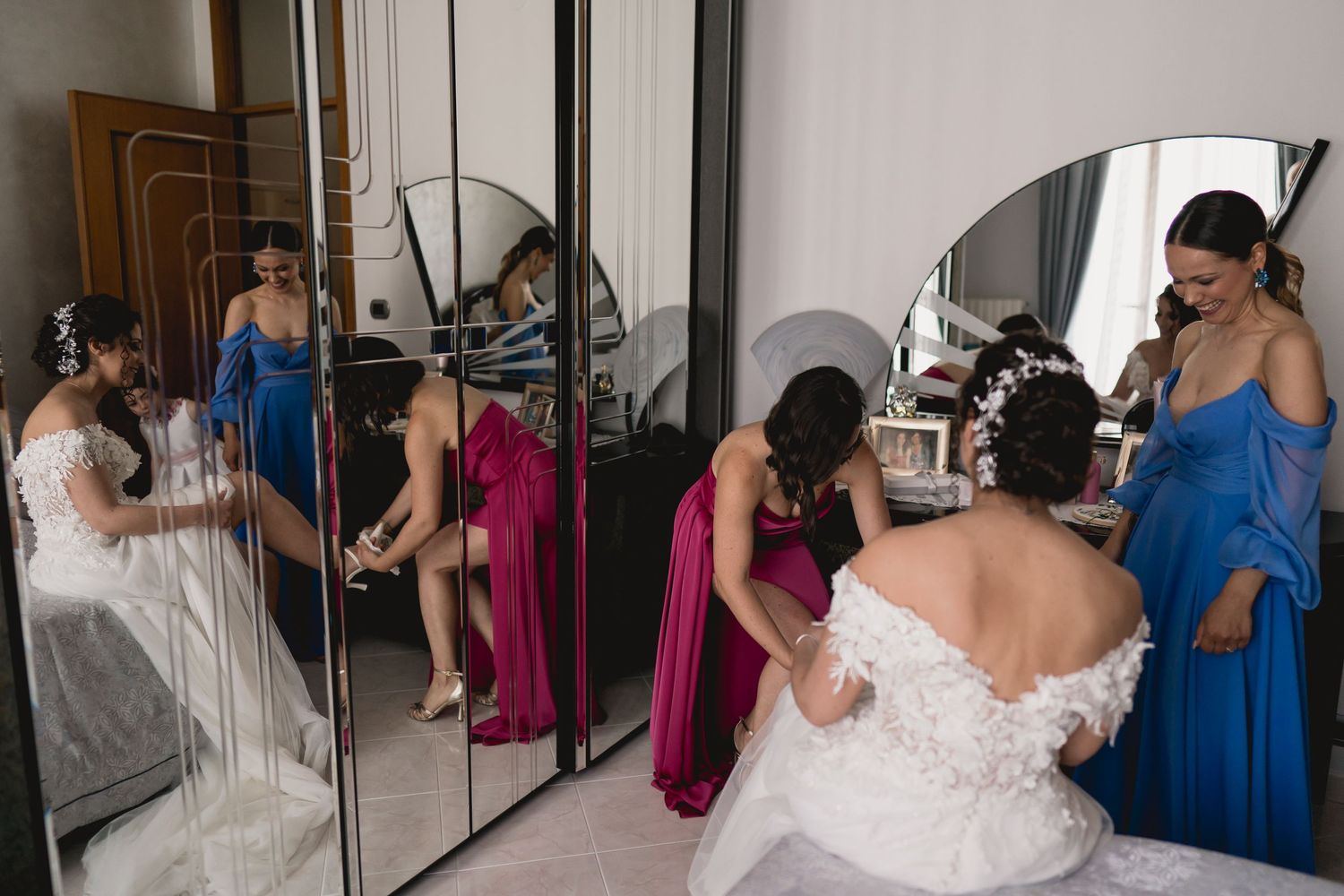 A group getting ready in a mirrored room with formal dresses in blue and magenta.