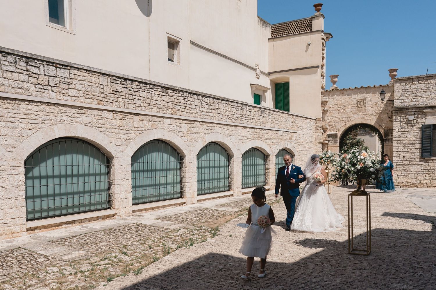 A bridal party walking through an arched Mediterranean courtyard.