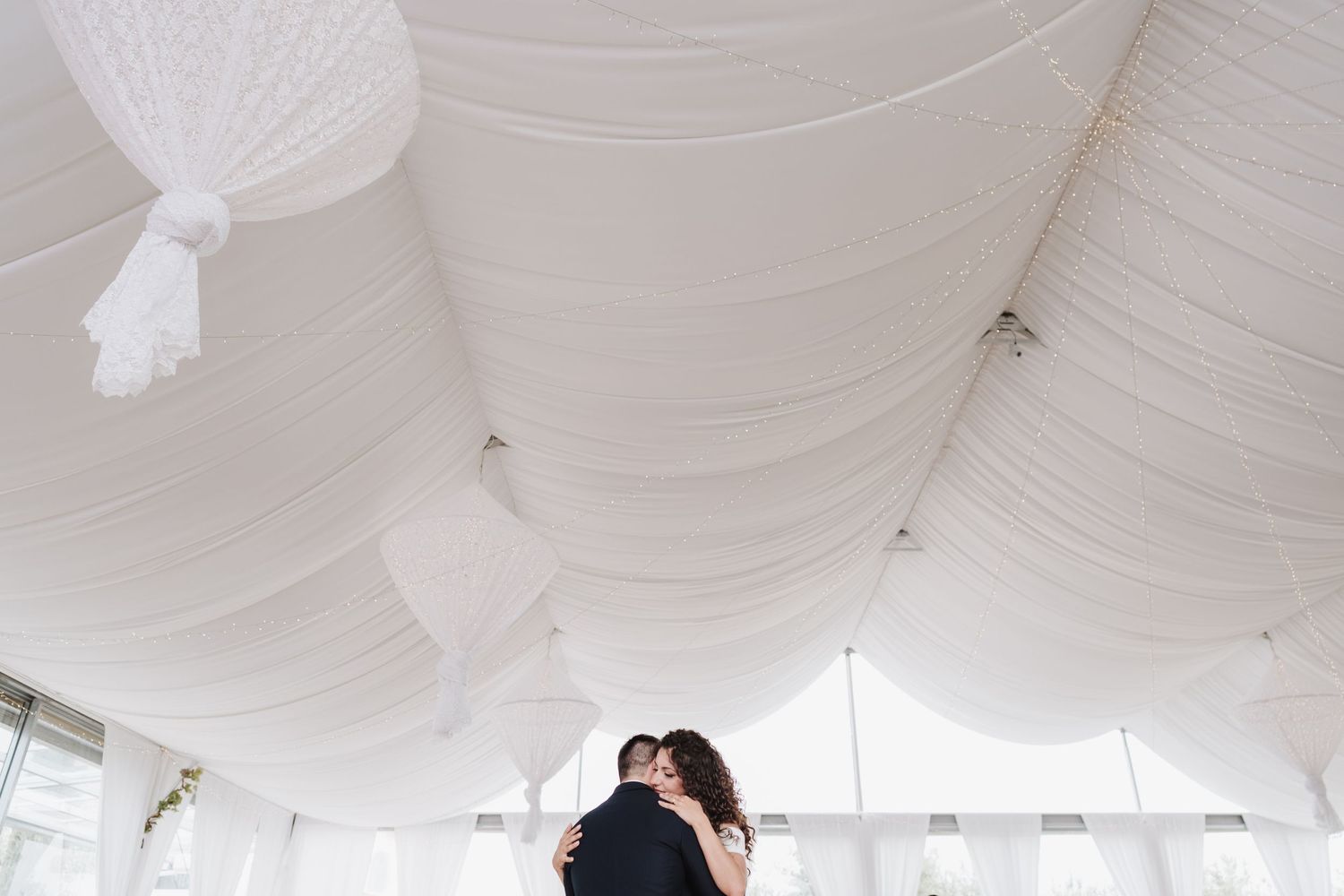 A tender moment under white draped ceiling at an elegant wedding reception.