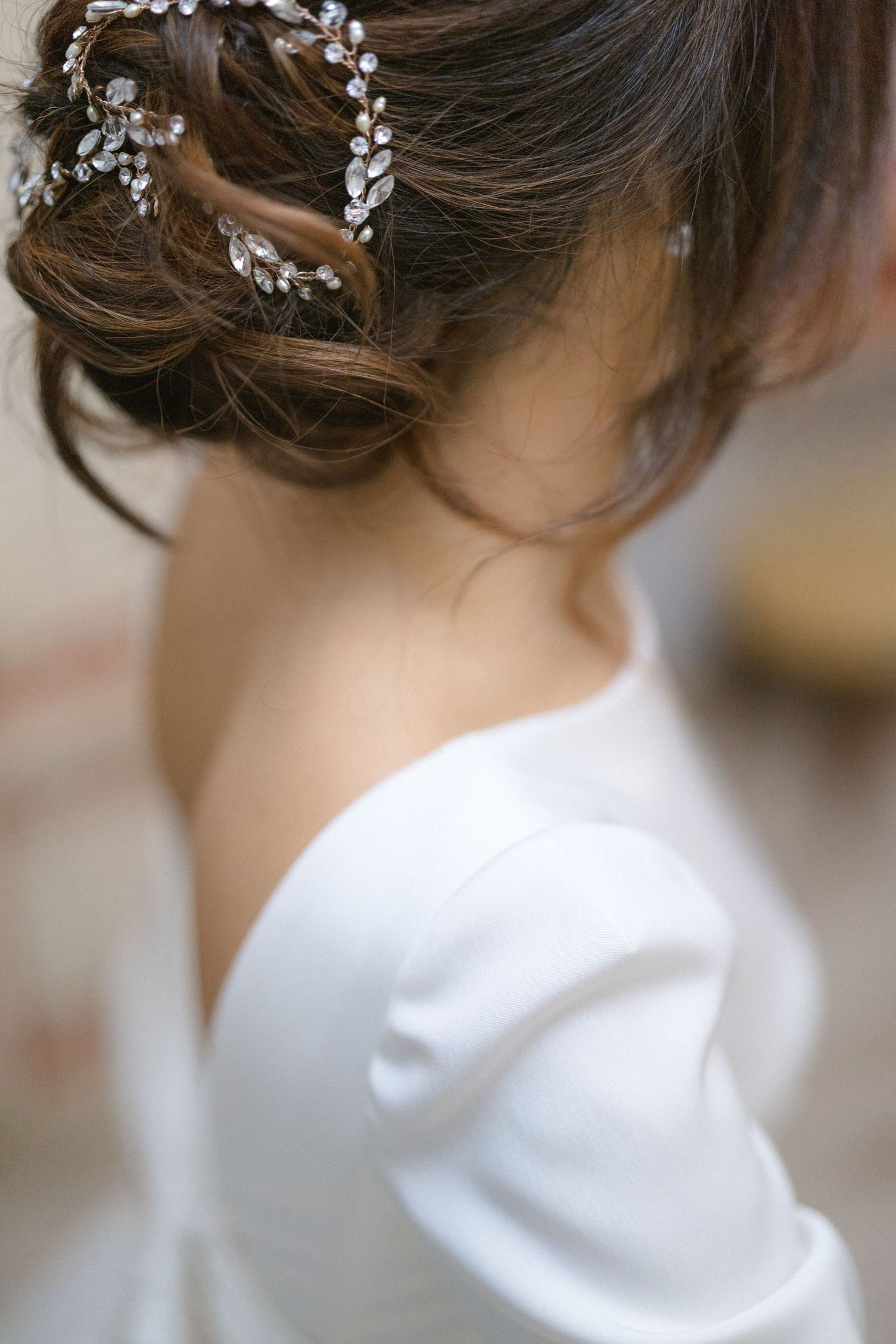 Close-up of bride's elegant updo hairstyle adorned with crystal hair vine accessory in white wedding dress.