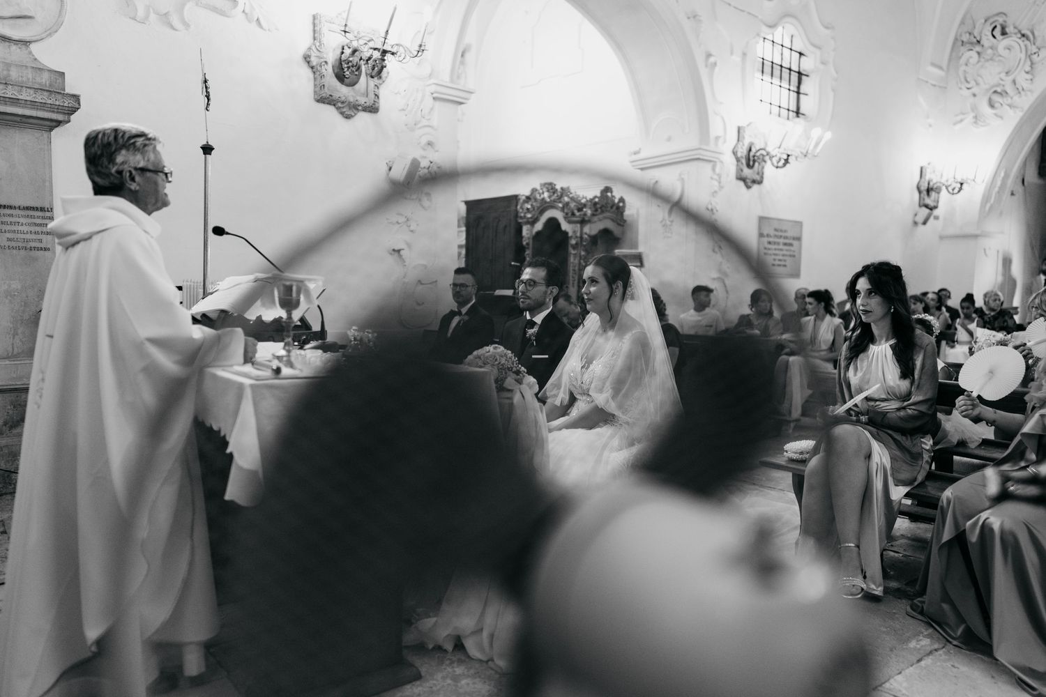 Black and white photo of a wedding ceremony in a historic church with arched architecture.