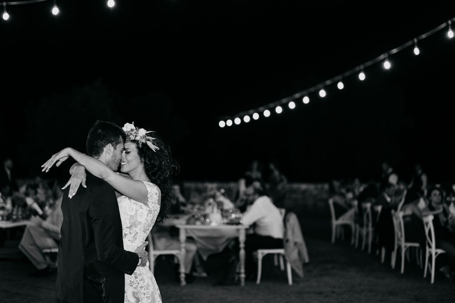 Dancers perform elegant ballroom dance moves under string lights at an outdoor evening event.