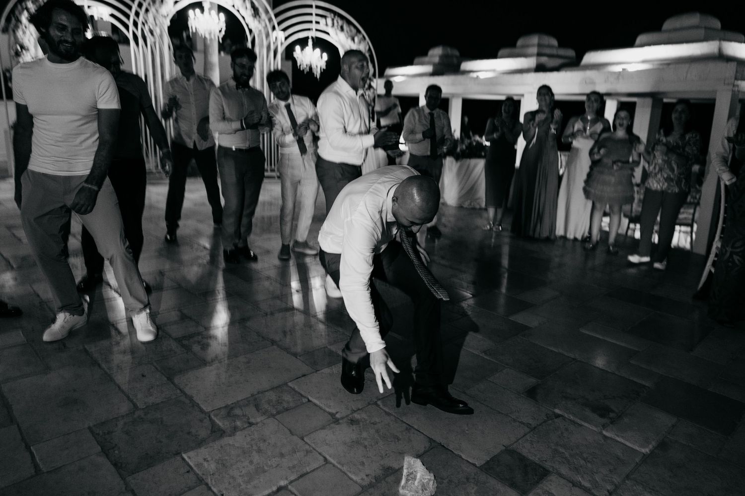 Wedding guests dancing on a tiled floor during an evening reception.