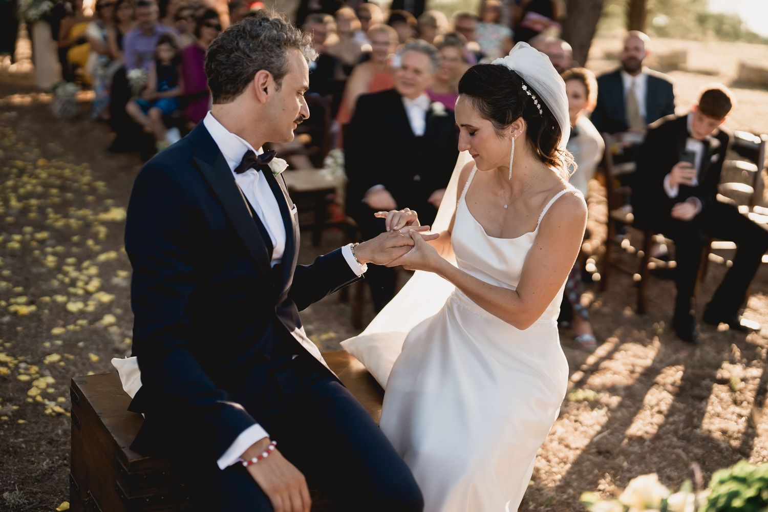 A couple shares an intimate moment during their outdoor wedding ceremony surrounded by autumn leaves.