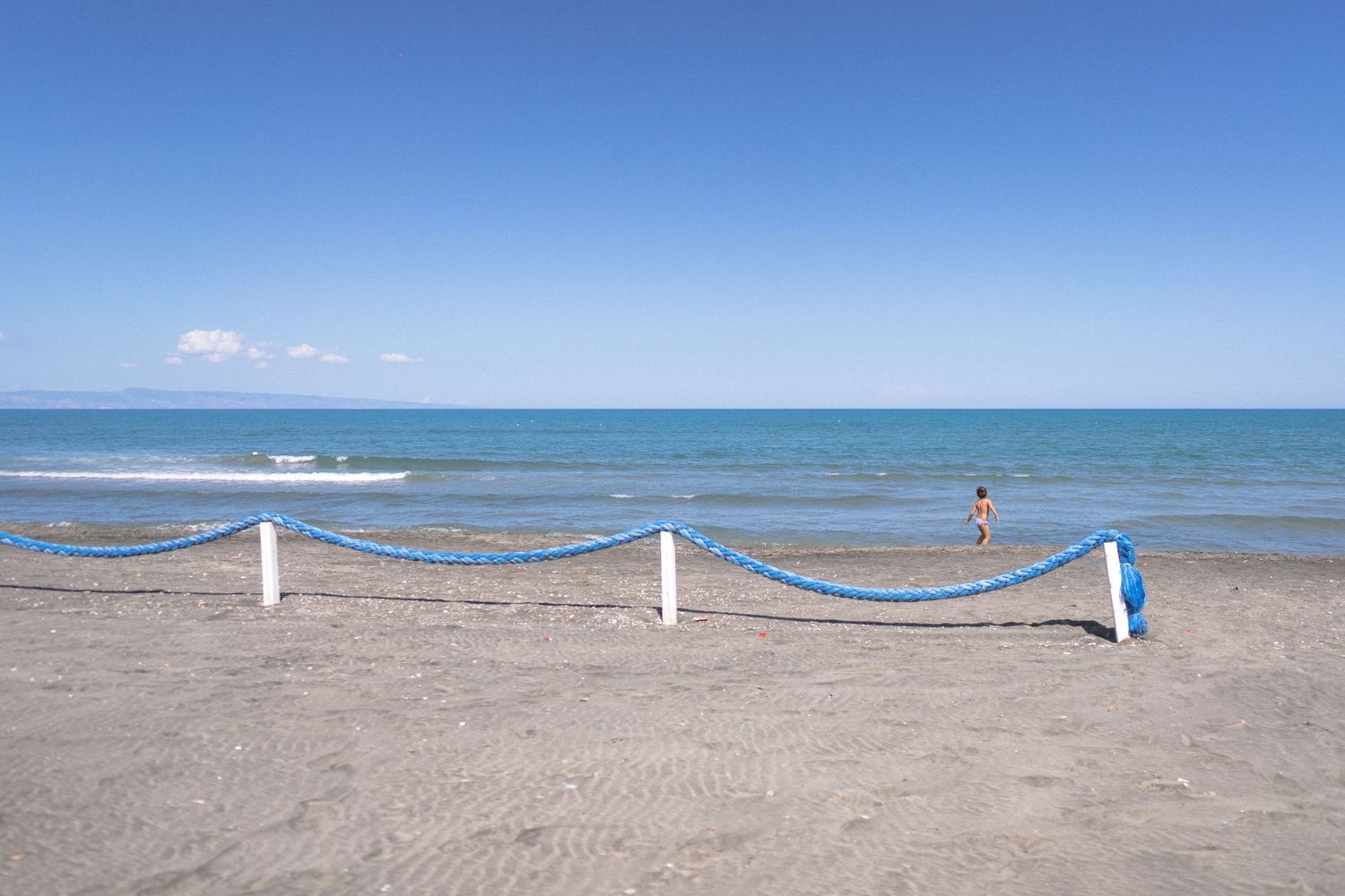 Panoramic view of a pristine beach with blue ocean waters and rope barriers.