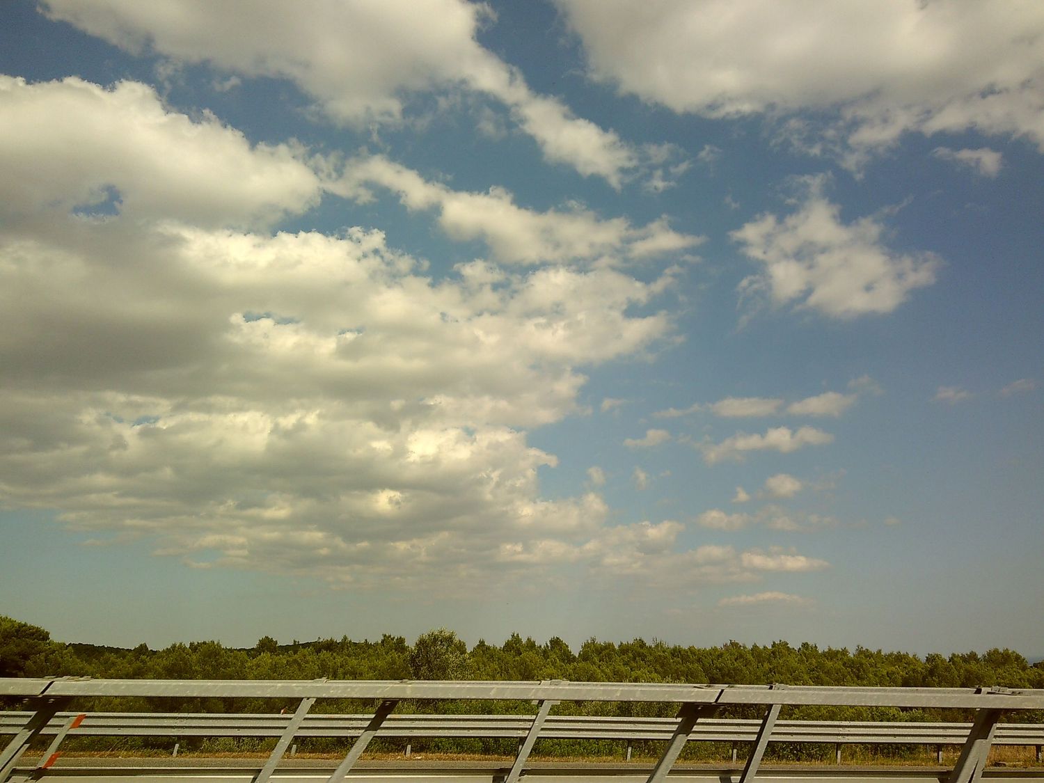 Beautiful blue sky with white puffy clouds over solar panels in a rural setting.