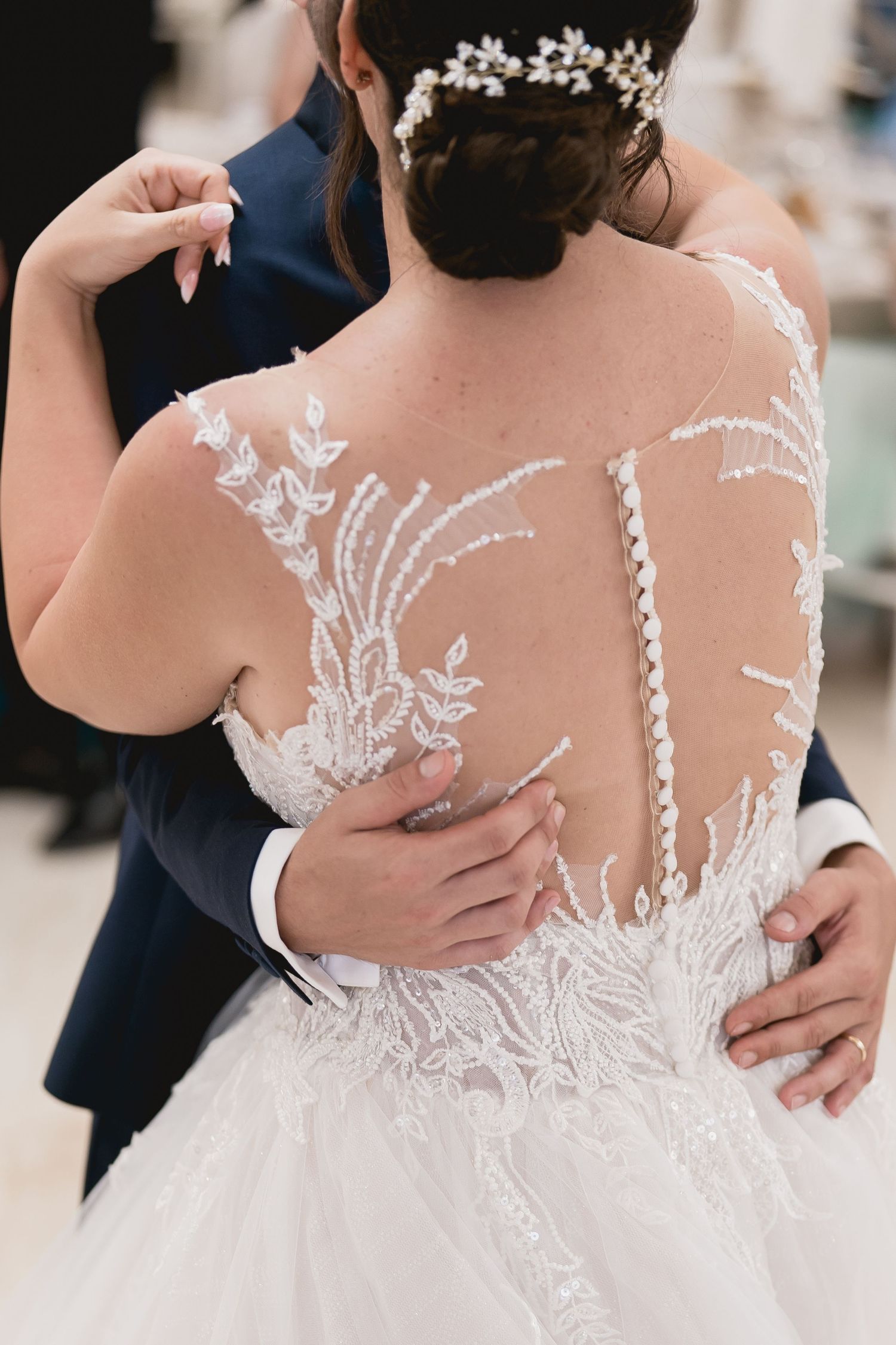 Close-up detail of intricate lace and sheer back design on a white wedding dress.