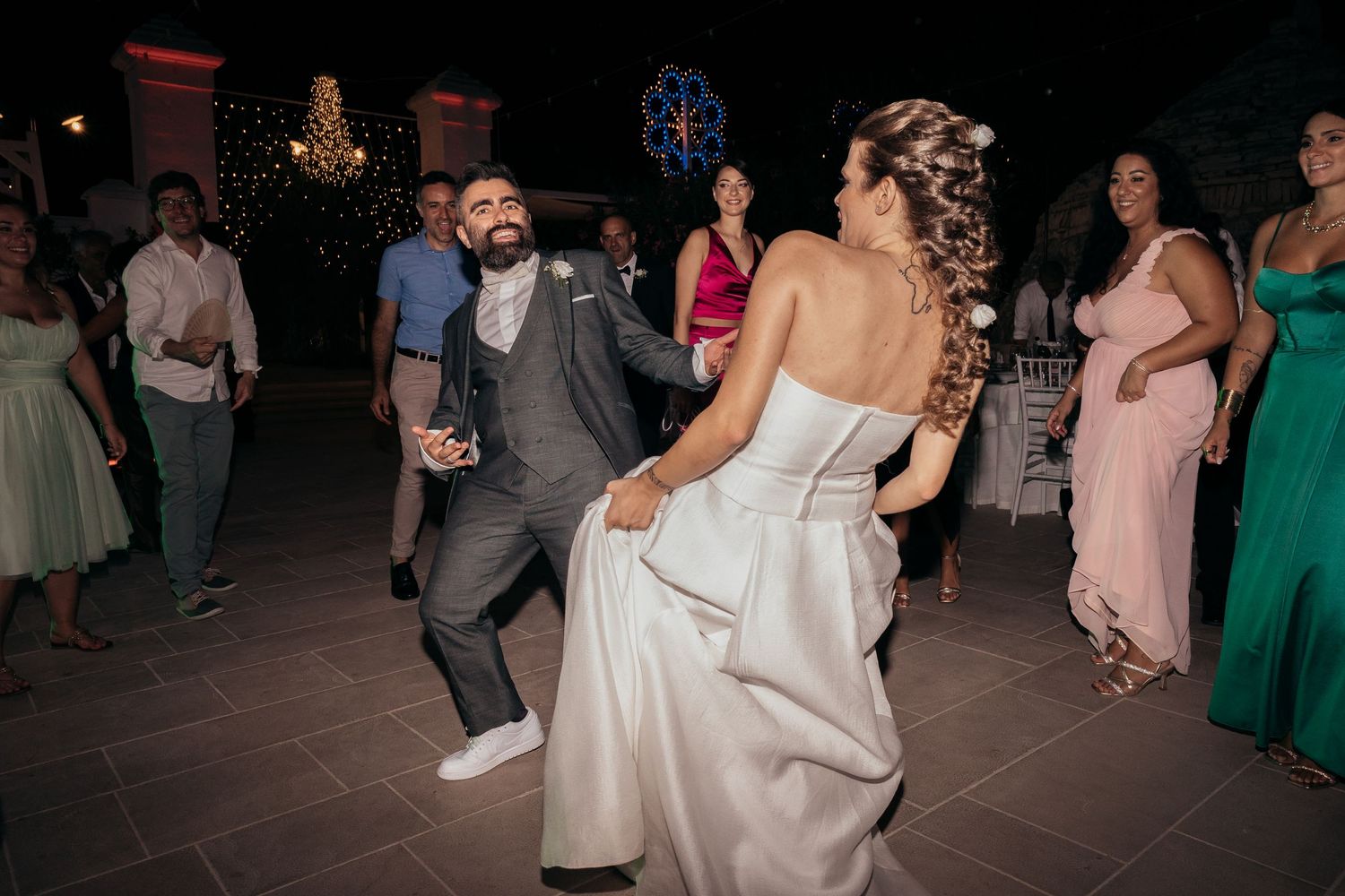 Couple showing off dance moves at their wedding reception while guests watch.