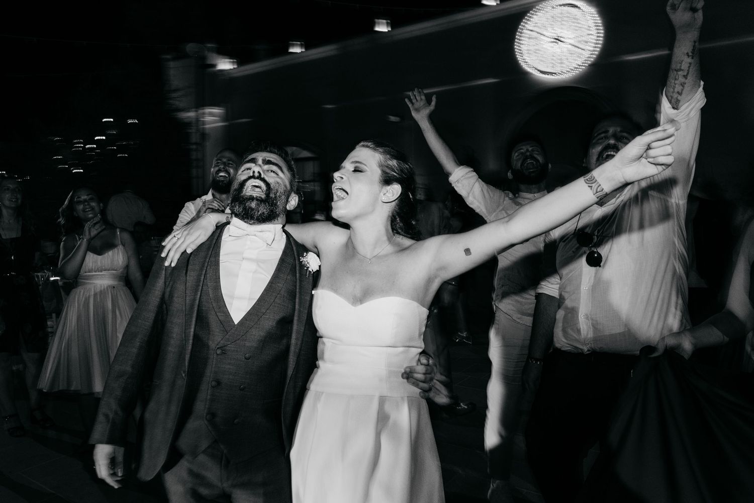 Wedding party members celebrate with joyful expressions during a black and white dance floor moment.
