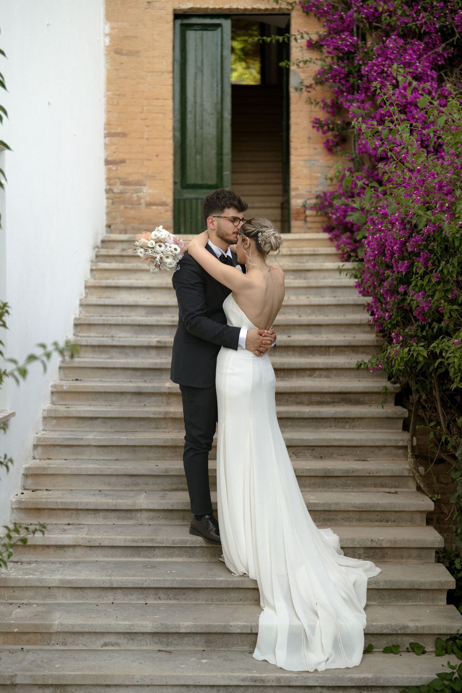 Romantic moment on stone steps adorned with blooming purple bougainvillea flowers.