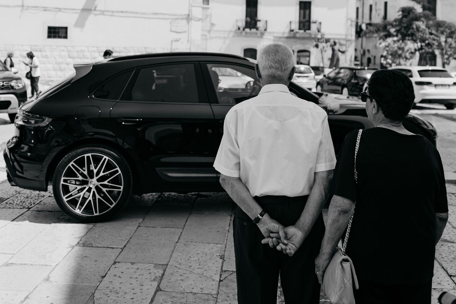 Wedding party members gathered outside near parked cars before the event.