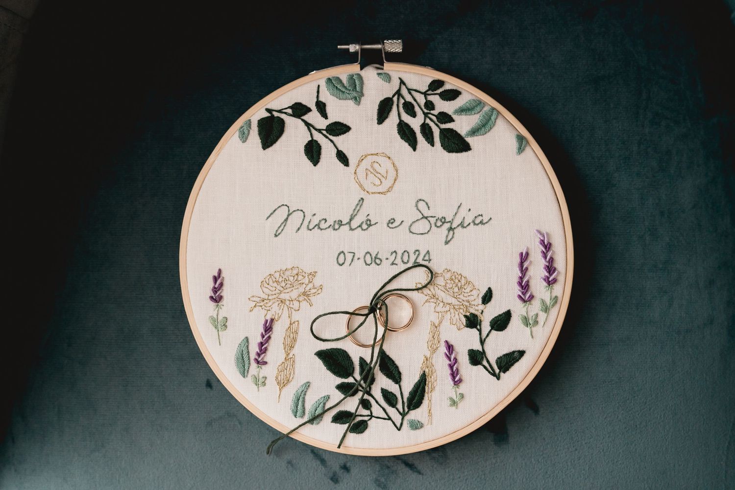 Decorative embroidery hoop with floral design and wedding date on dark background.