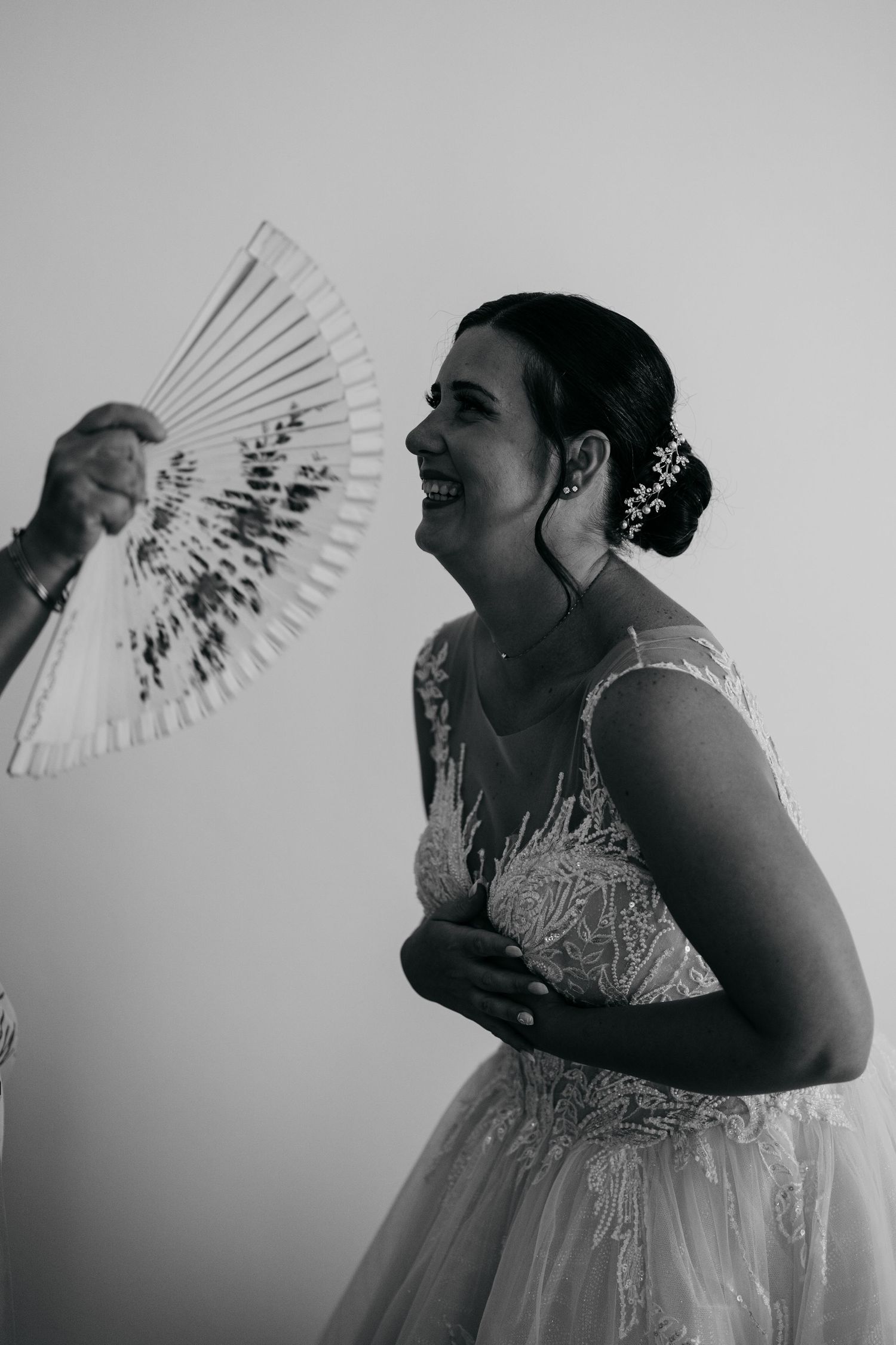 A joyful moment captured in black and white as a bride holds a decorative fan.