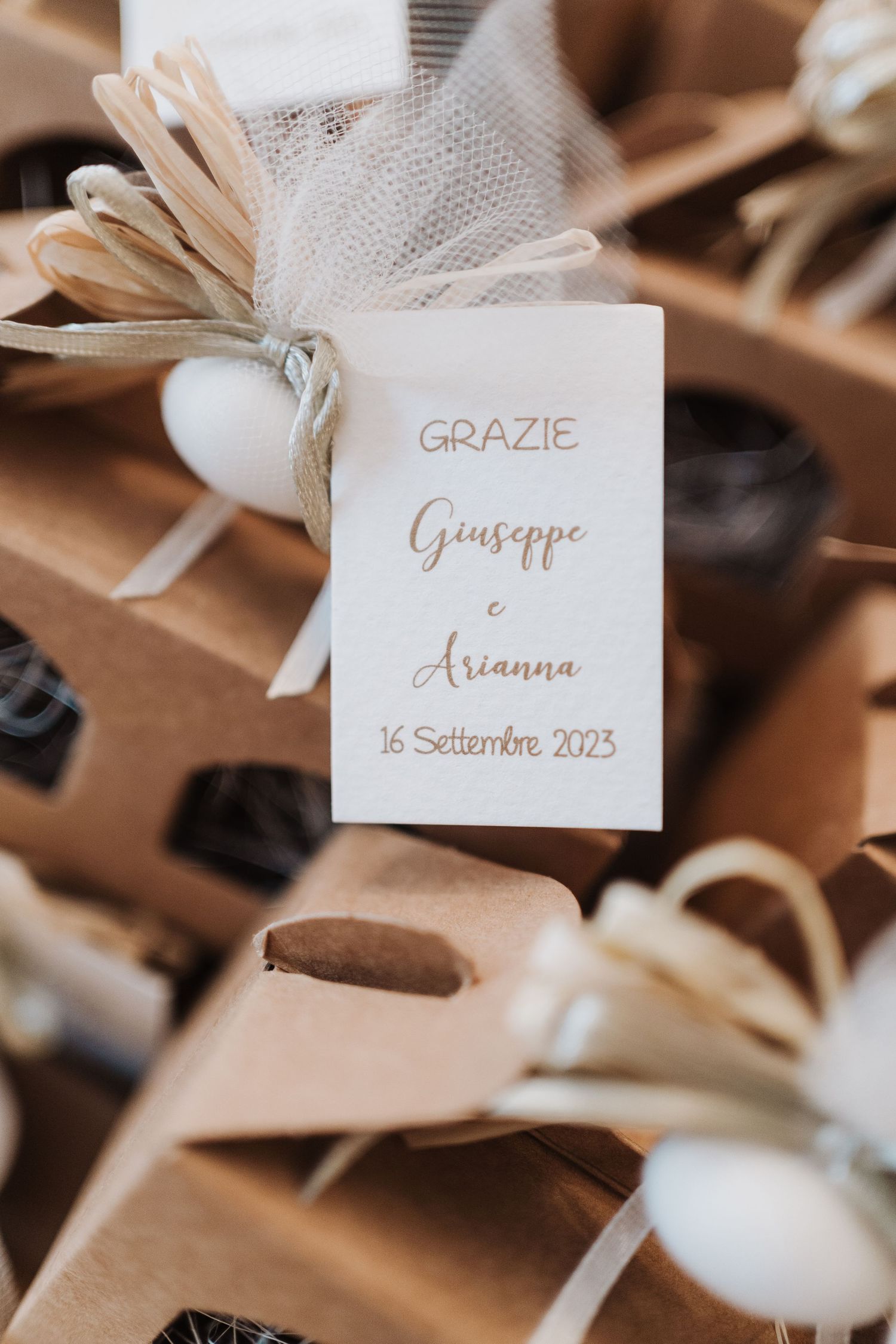 A wedding favor tag with 'Grazie Giuseppe e Arianna' and date written in elegant script.