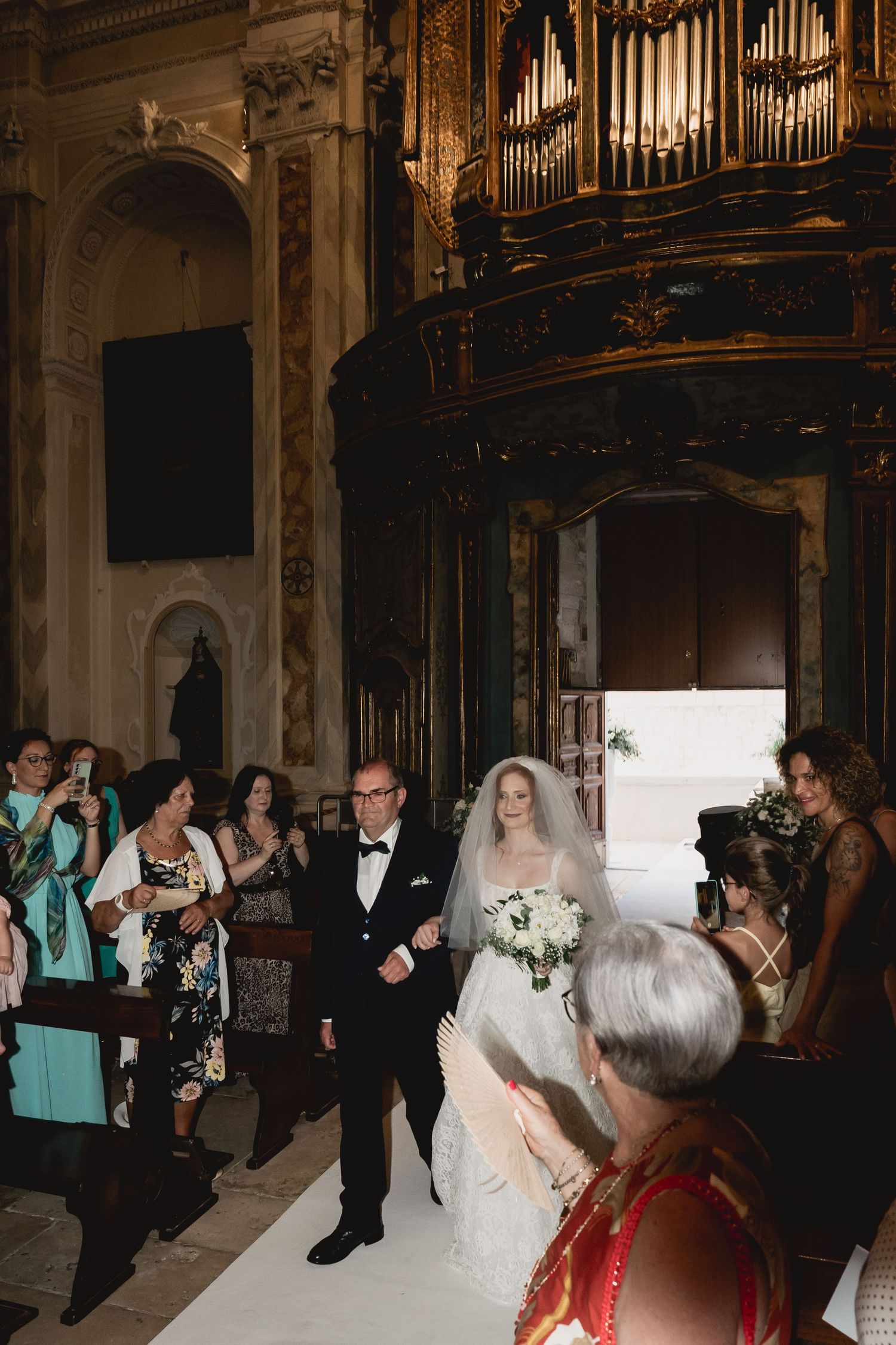 Wedding ceremony procession in ornate church interior with vintage pipe organ.