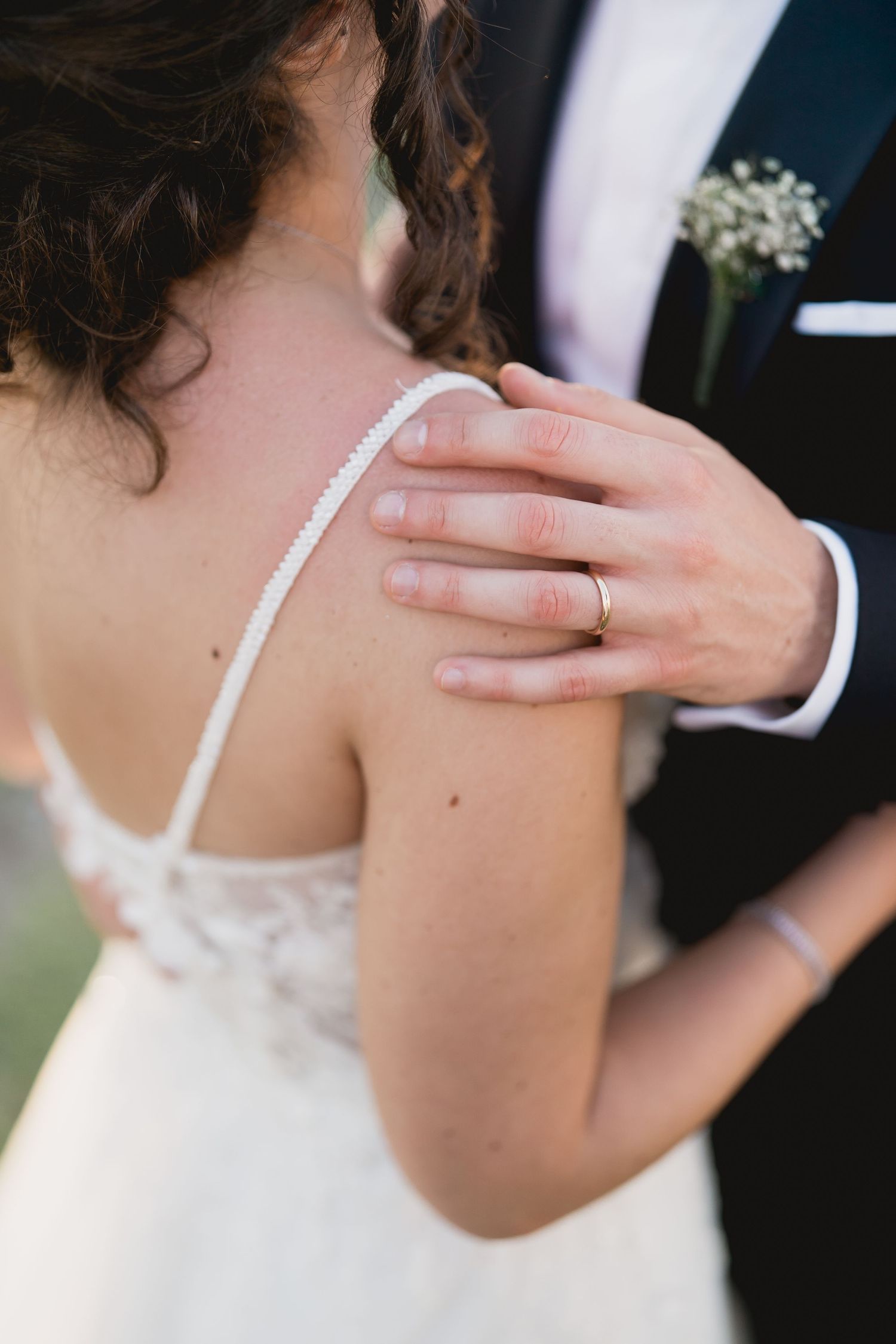 A close-up detail of a hand on a beaded wedding dress strap.