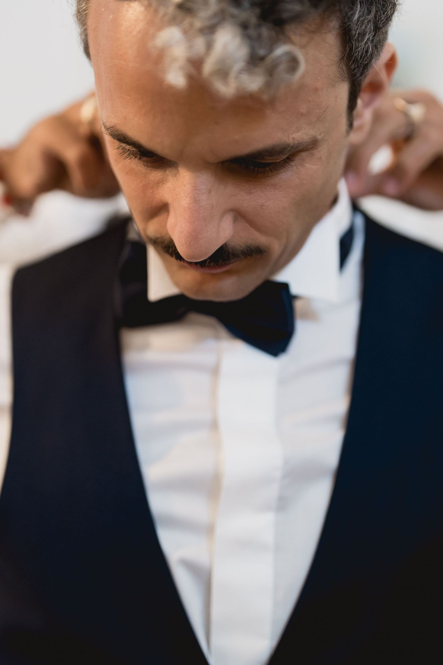 Close up of a formally dressed person wearing a bow tie with smoke rising above.