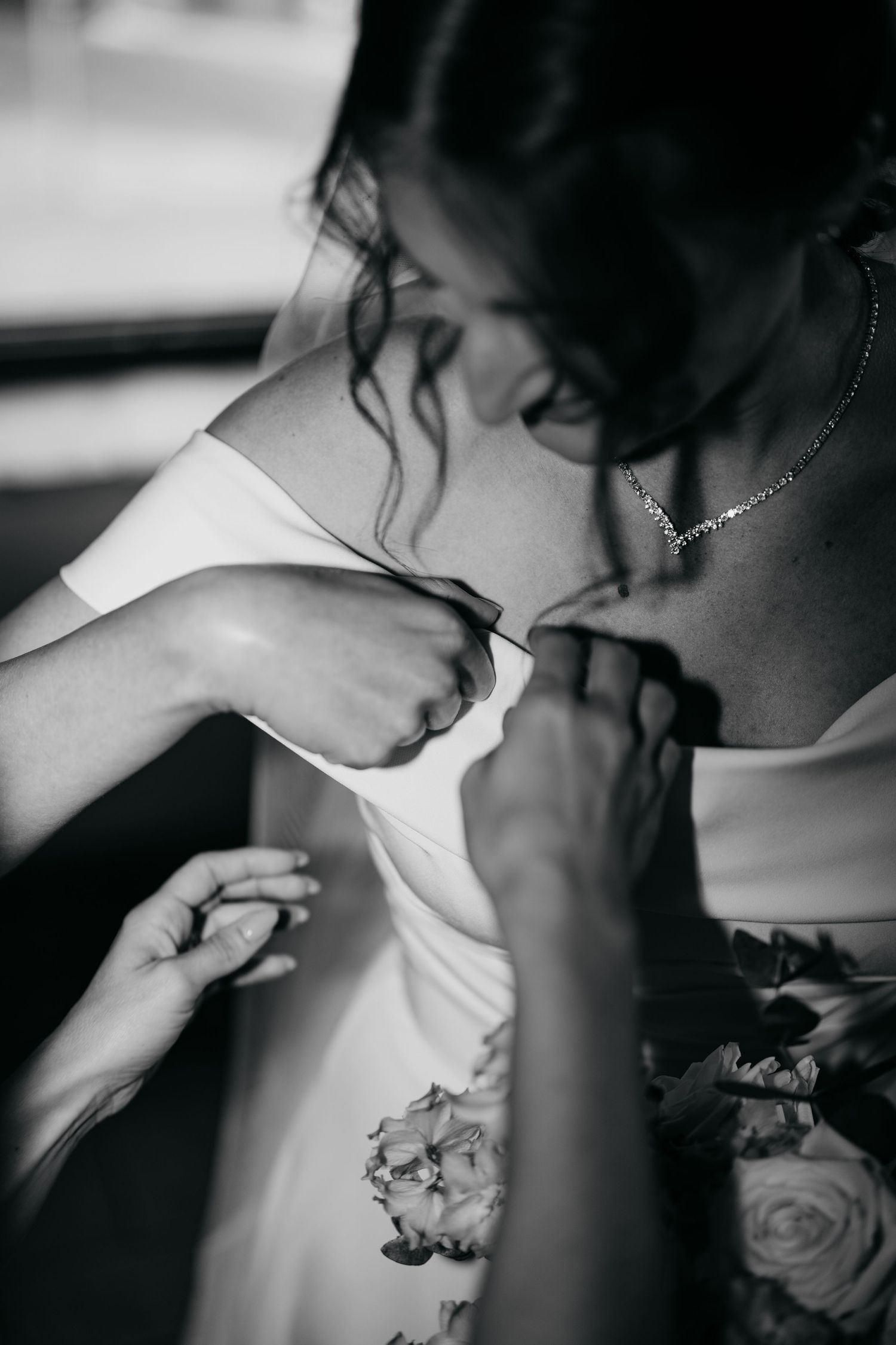 Close-up black and white photo of dress adjustments being made with delicate detail.