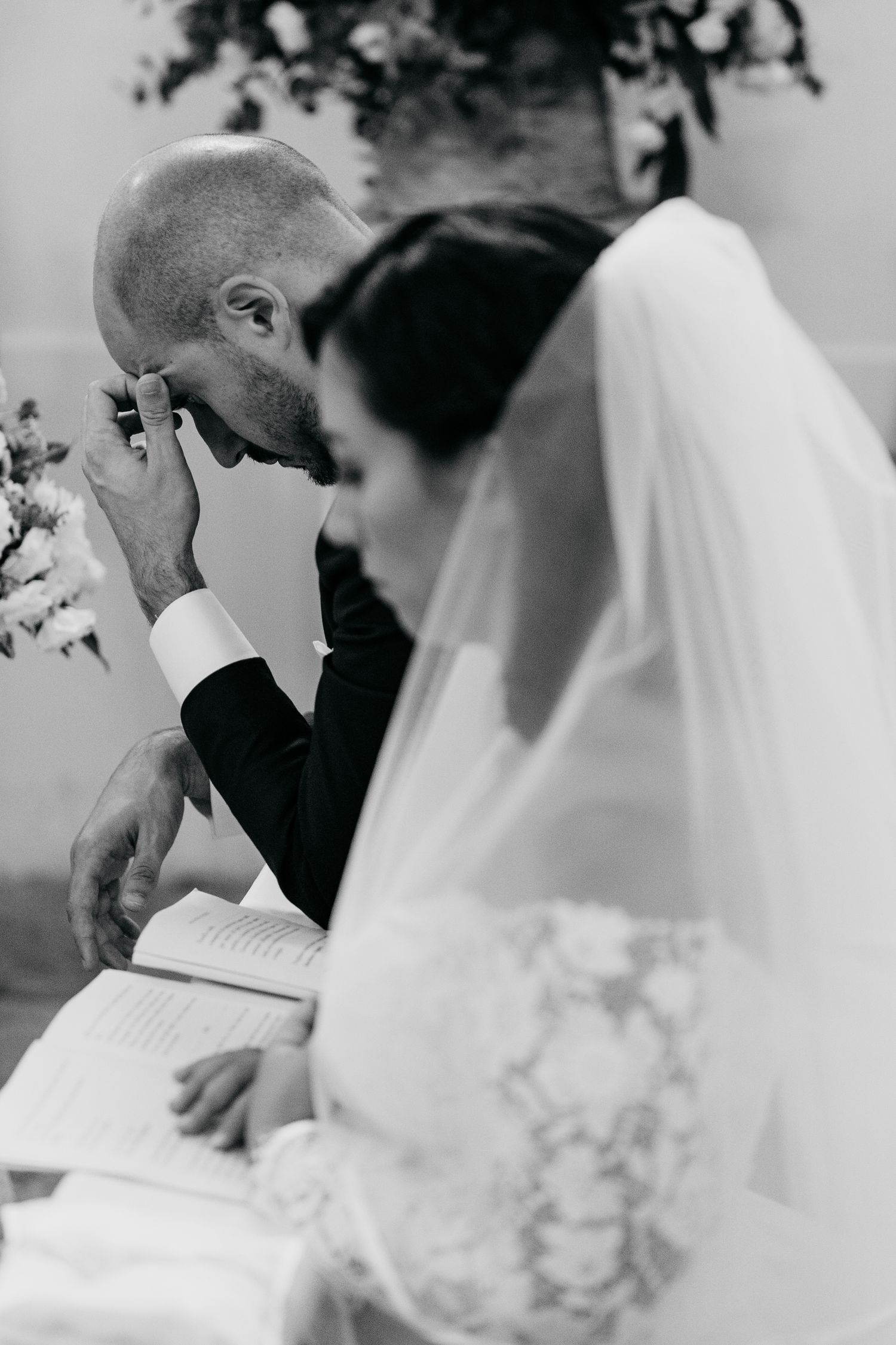 A black and white photo series showing a couple signing their marriage documents during an outdoor wedding ceremony.