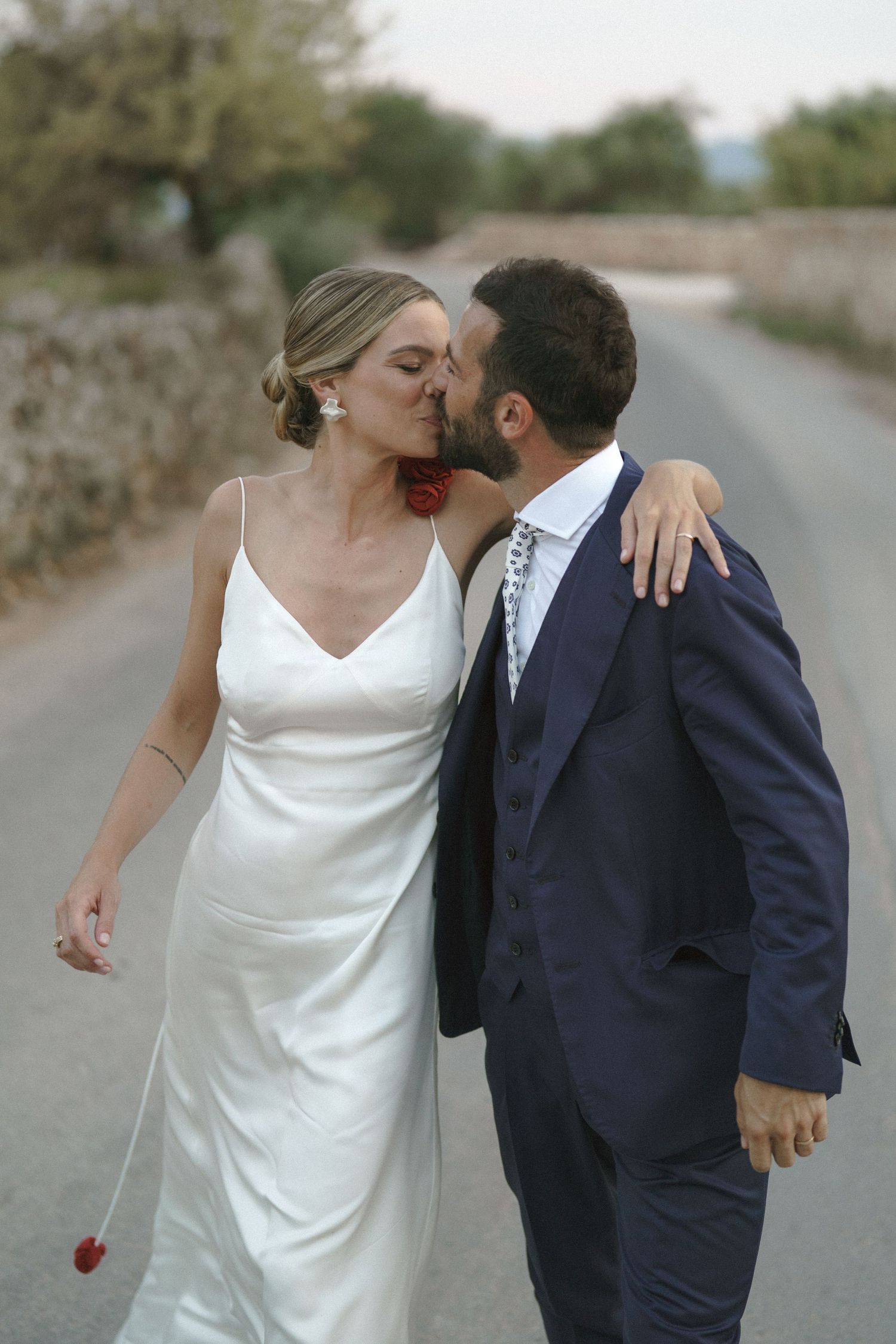A romantic moment between newlyweds on a countryside road.