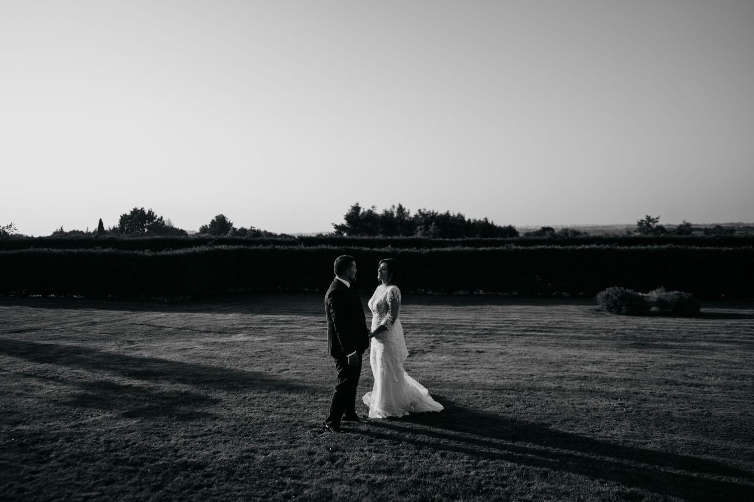 Panoramic black and white landscape view of a wedding ceremony in a vast open field.