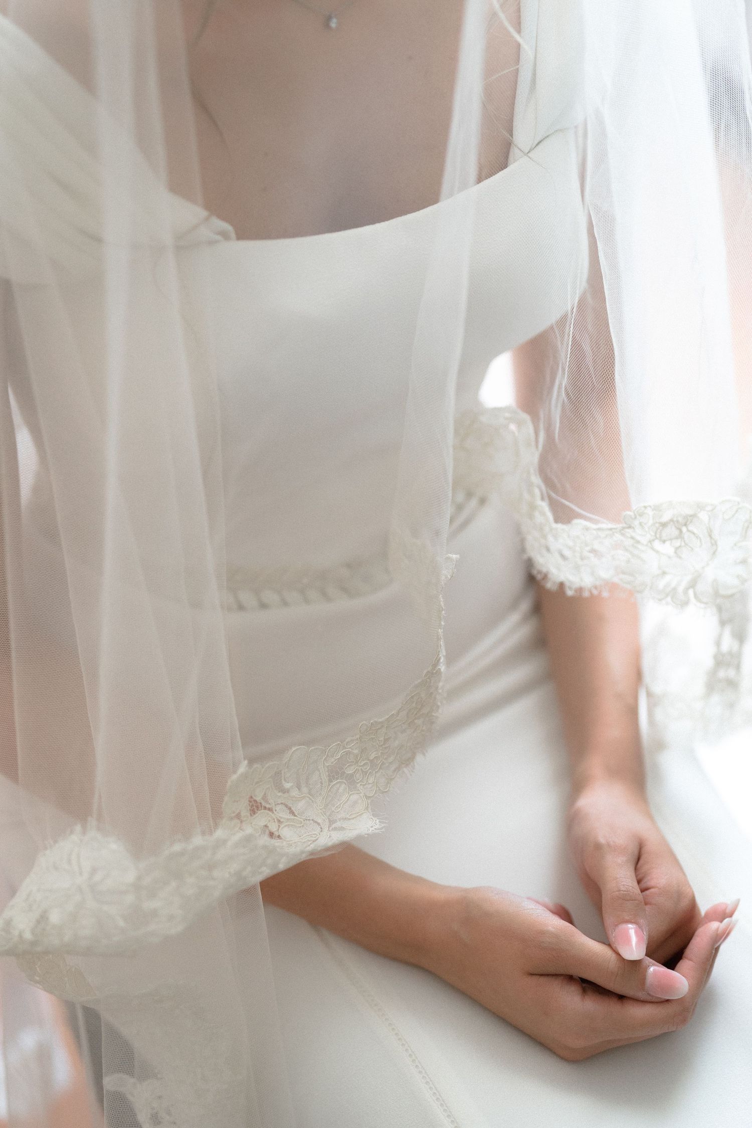 Close-up details of delicate lace and fabric on a white wedding dress.