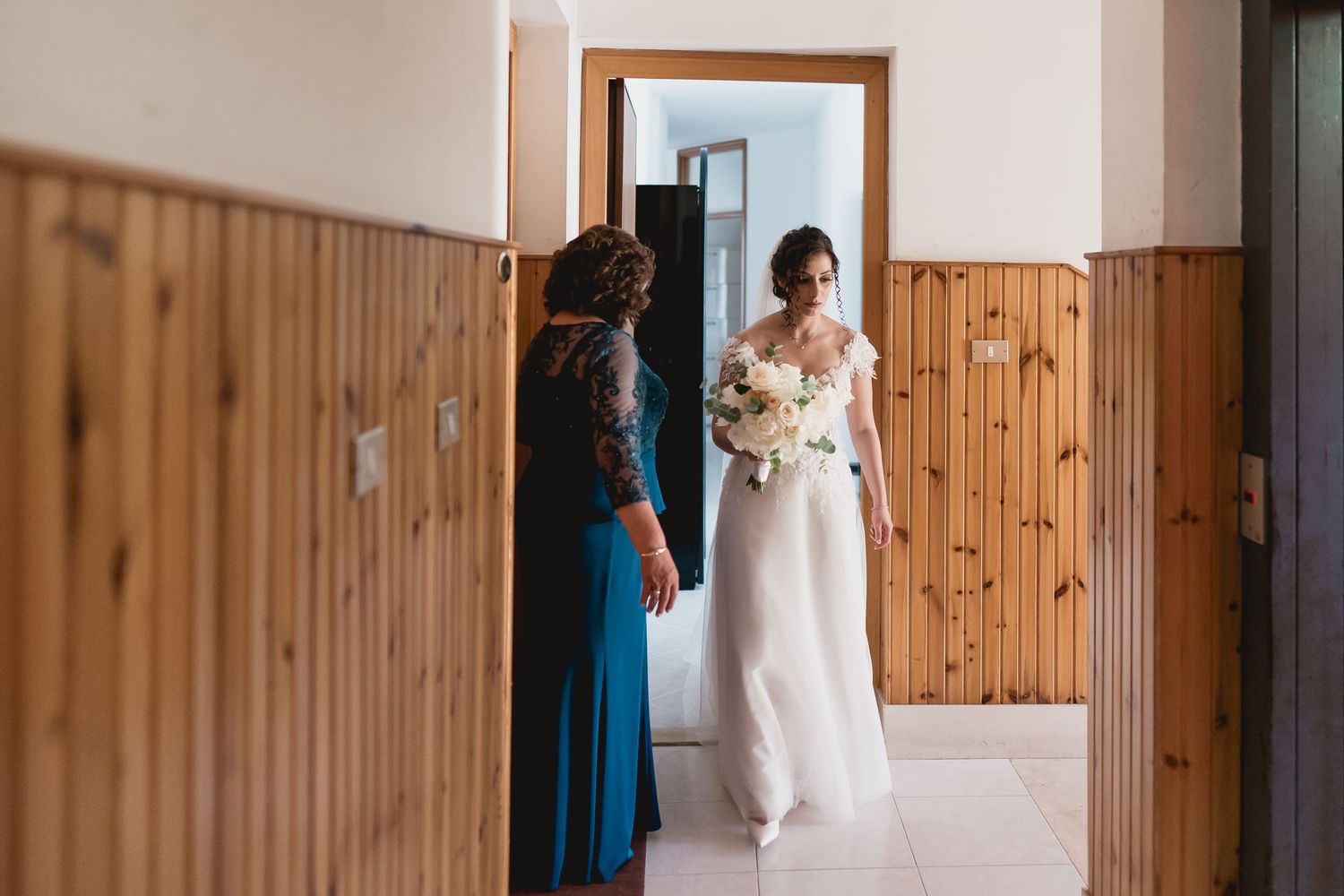 A corridor with wood-paneled walls showing a wedding dress being revealed.