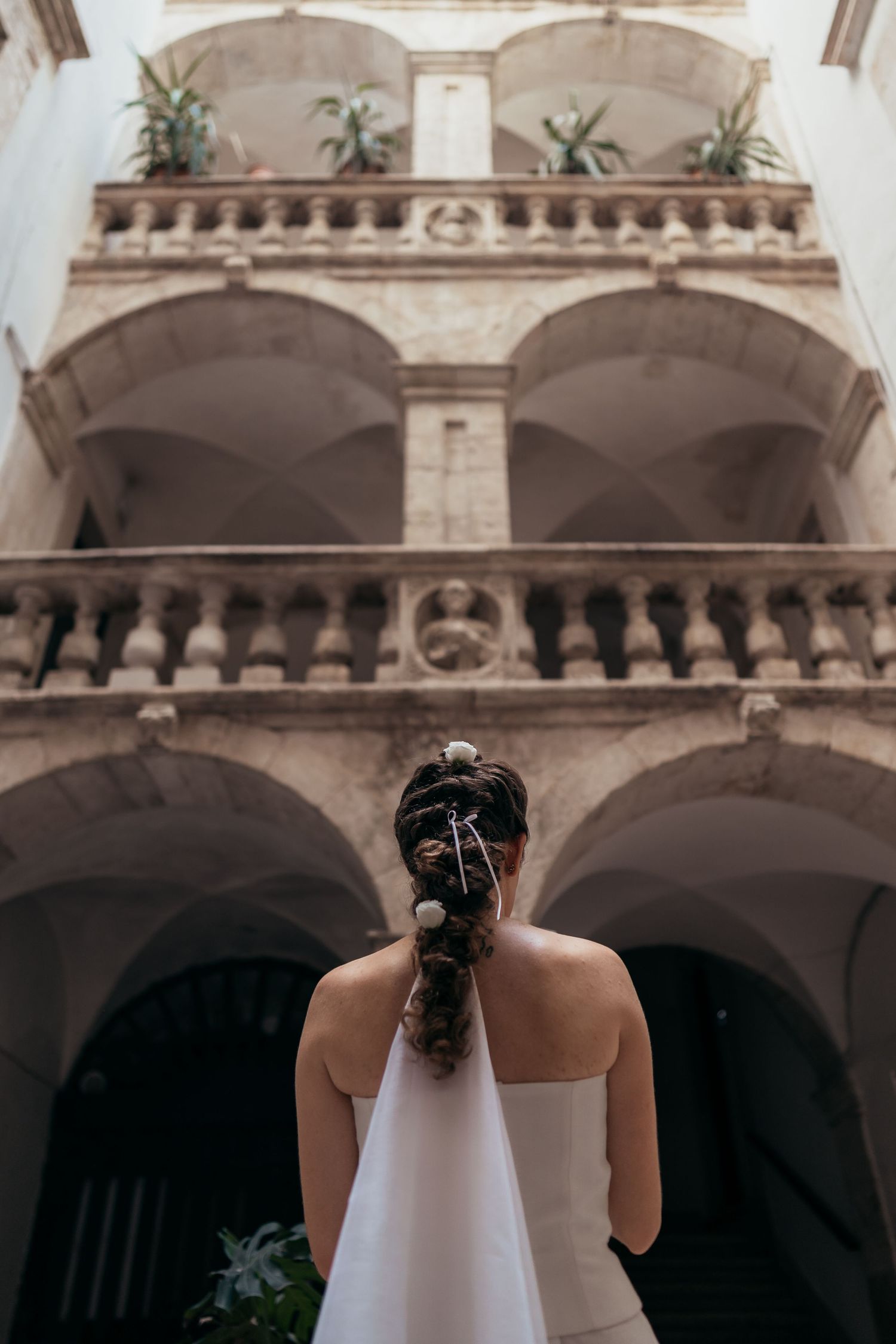 View from below of a classical stone balcony with arches and decorative architecture at a wedding venue.