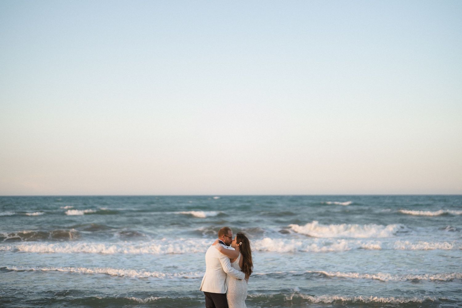 Scenic beach landscape with waves crashing on the shore under a bright blue sky.
