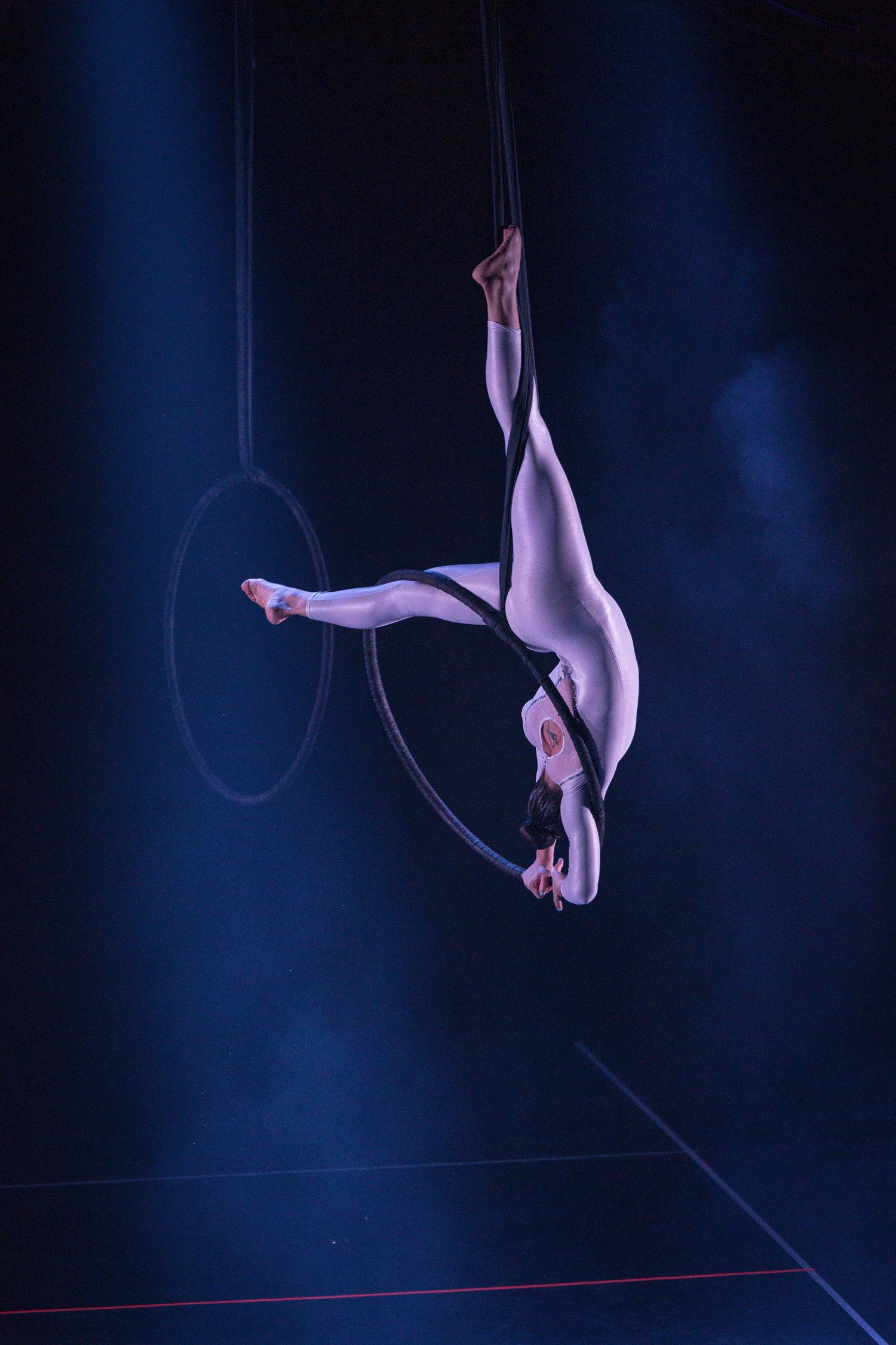 Aerial silk performer gracefully executes a series of dynamic poses against a dark blue background in this sequence.