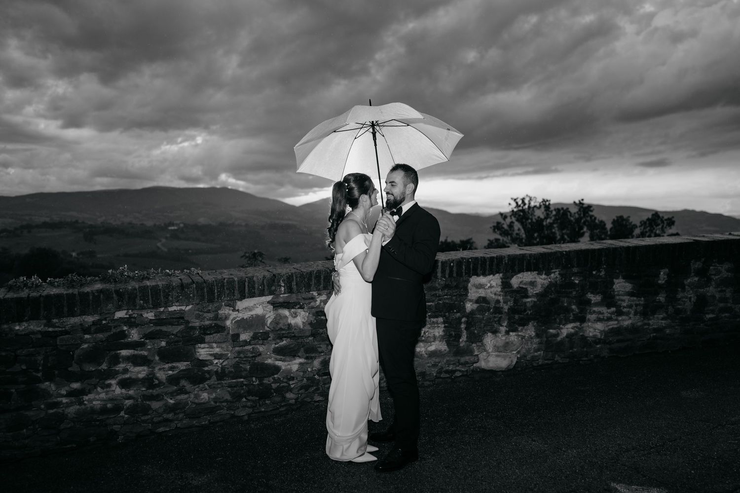 Dramatic black and white landscape photos of a couple with stormy skies.