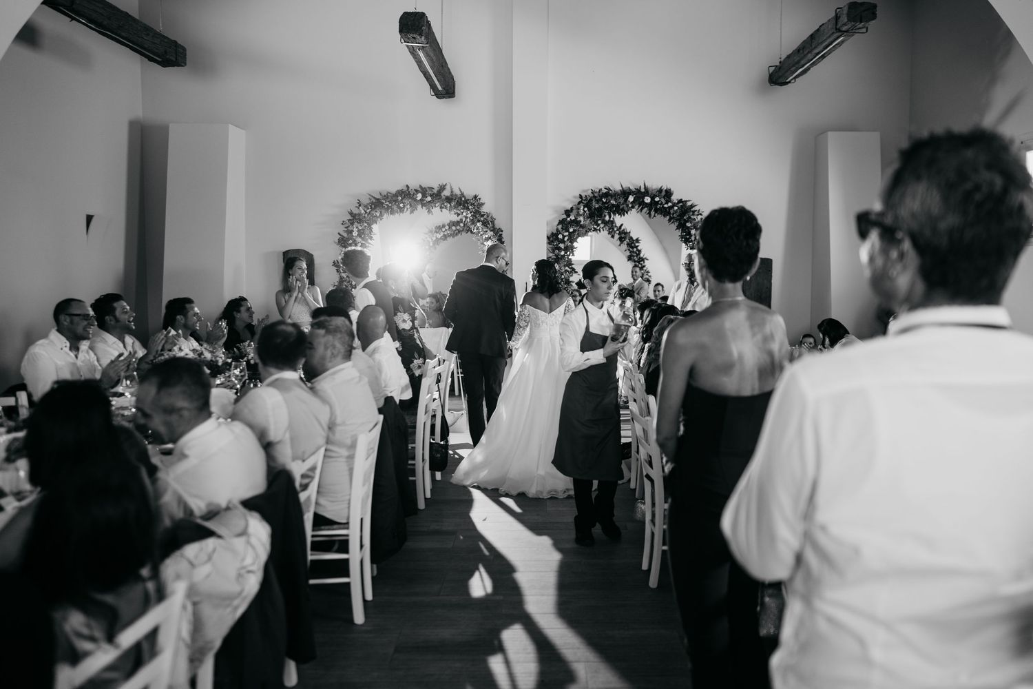 Wedding reception guests dancing and celebrating in a dimly lit venue.