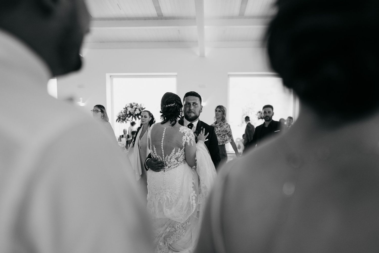 Wedding guests gather in a bright indoor space for a celebratory moment.
