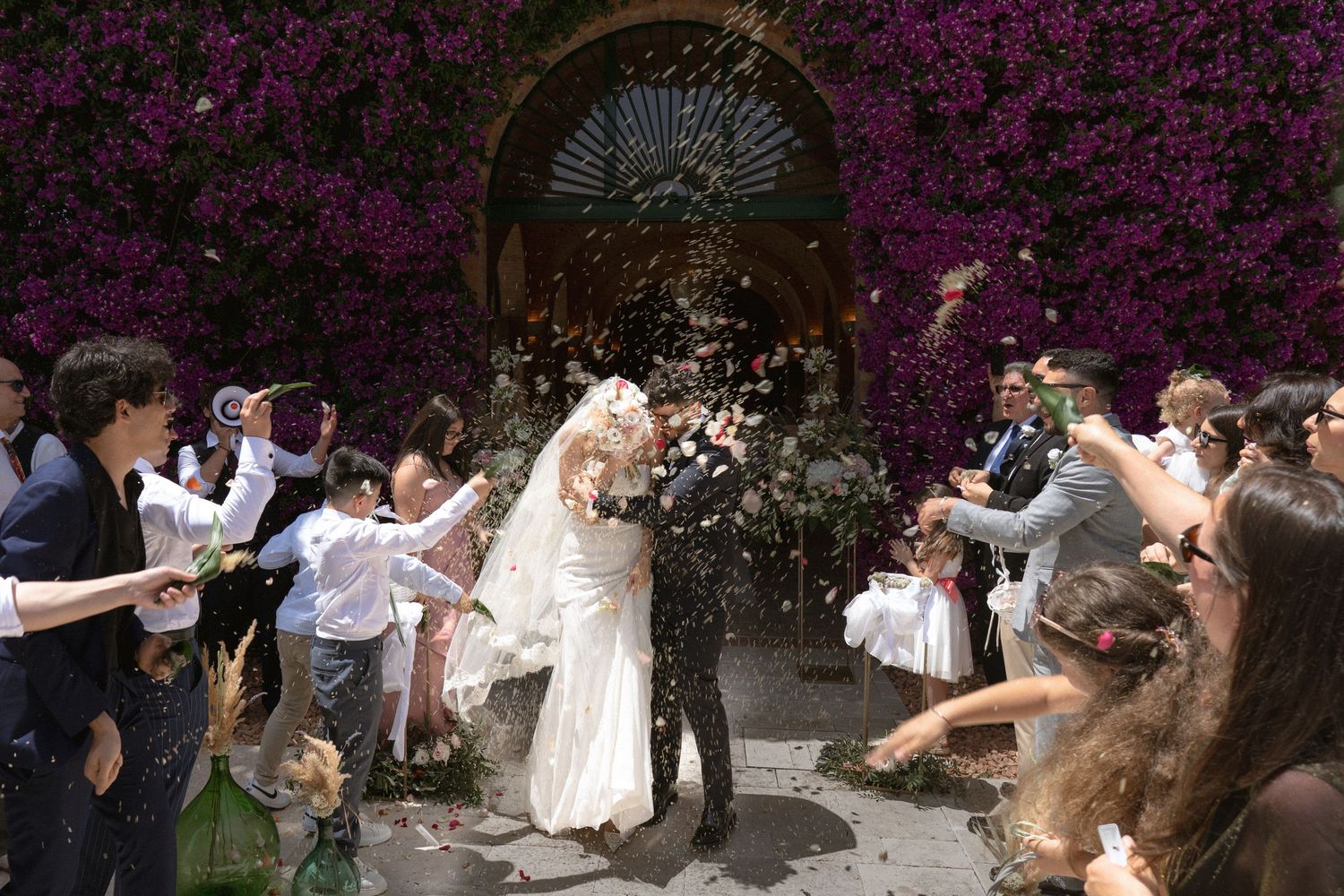 Outdoor wedding celebration with vibrant purple bougainvillea flowers creating a romantic backdrop.