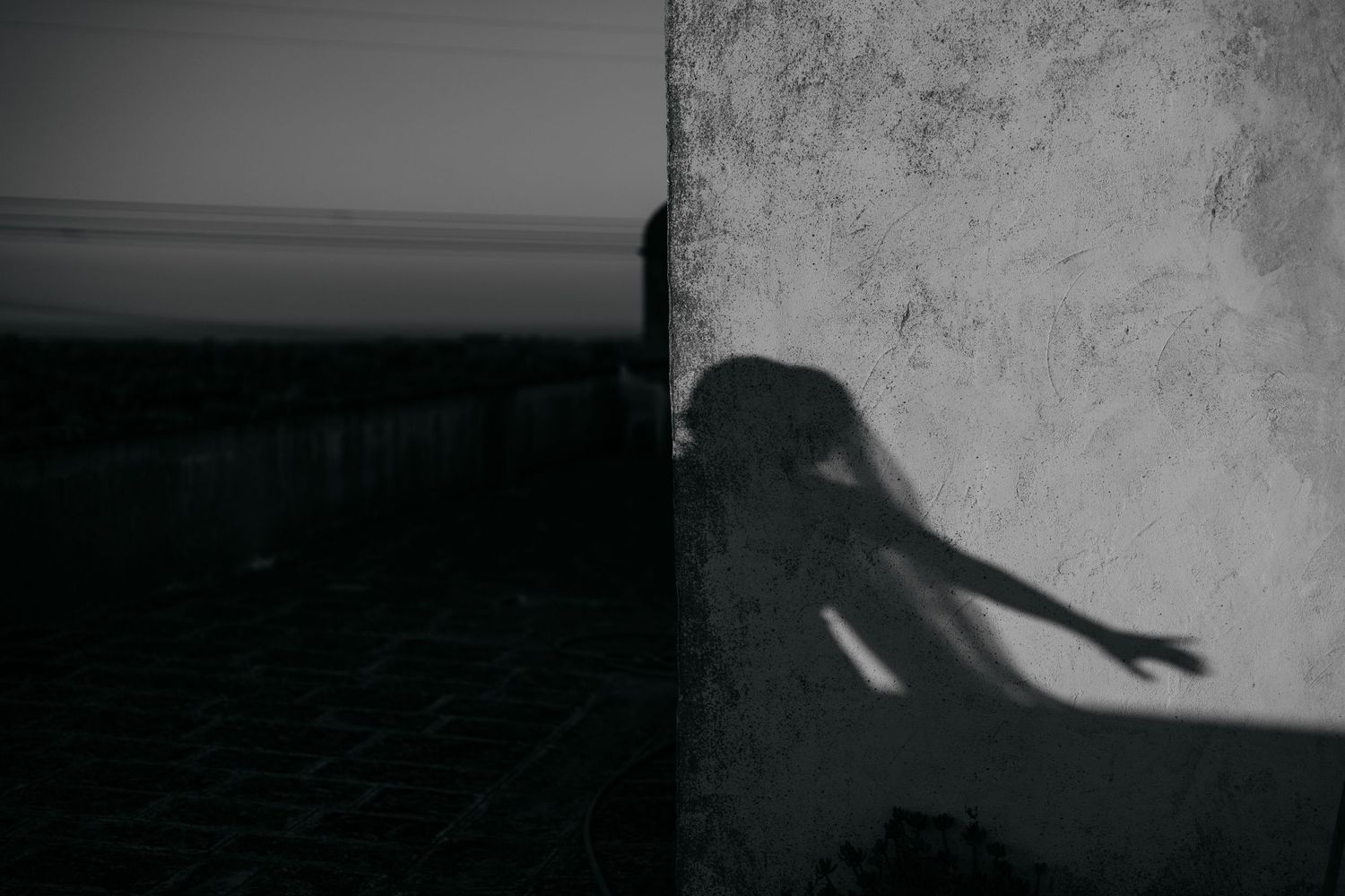 A haunting shadow of a figure cast on a textured wall in black and white.
