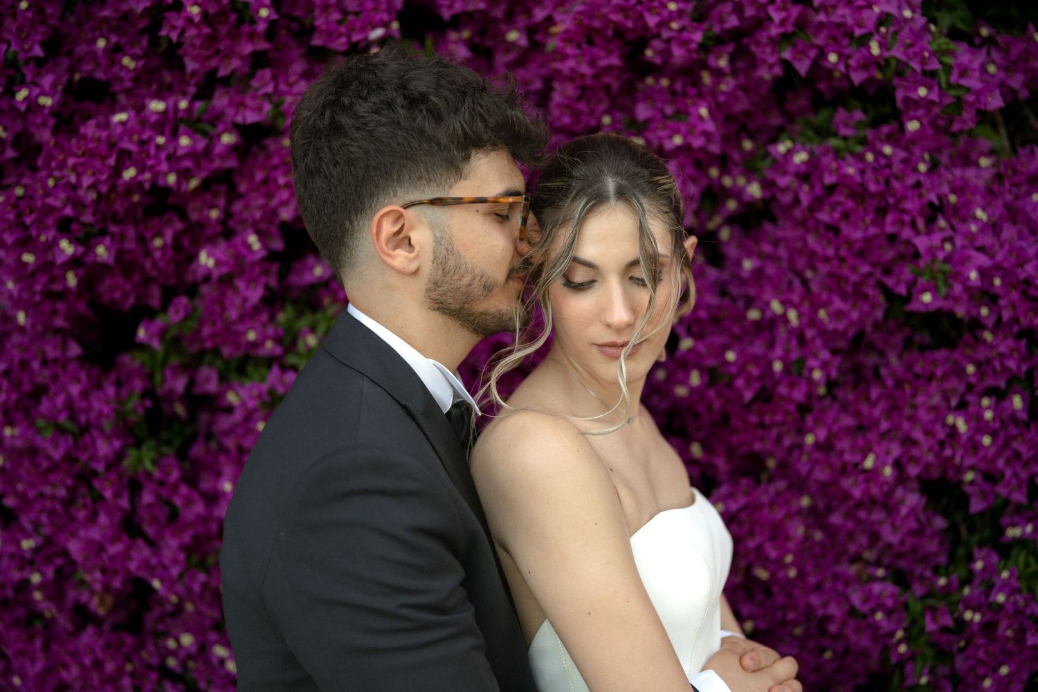 Romantic moment against vibrant purple bougainvillea backdrop.