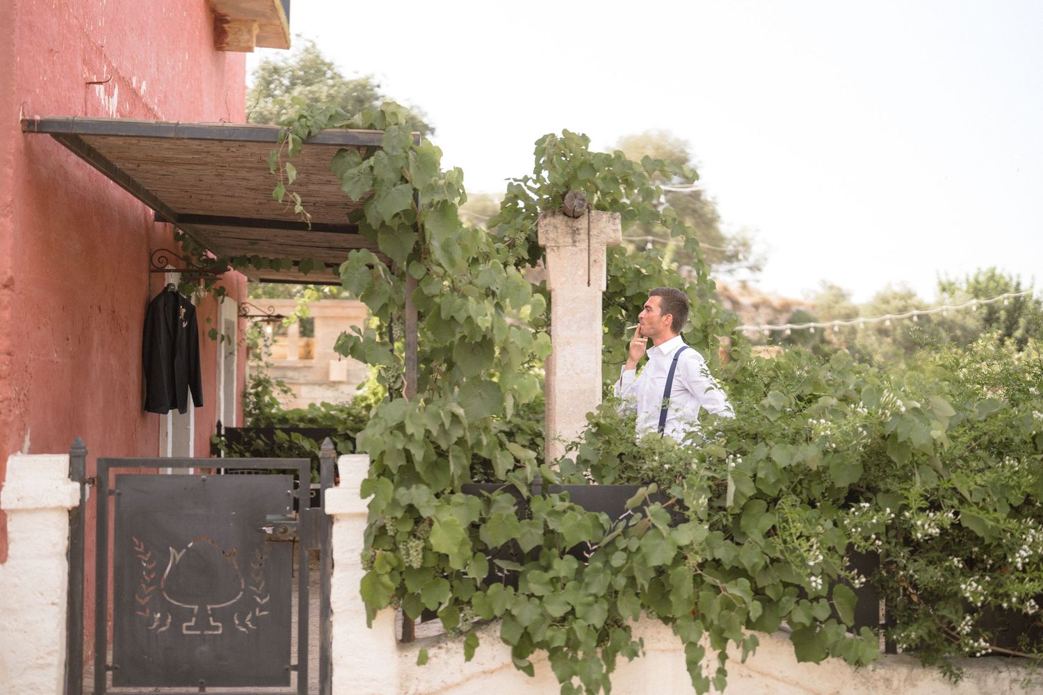 Pink stucco building exterior with green vines growing along the walls and arched doorways.