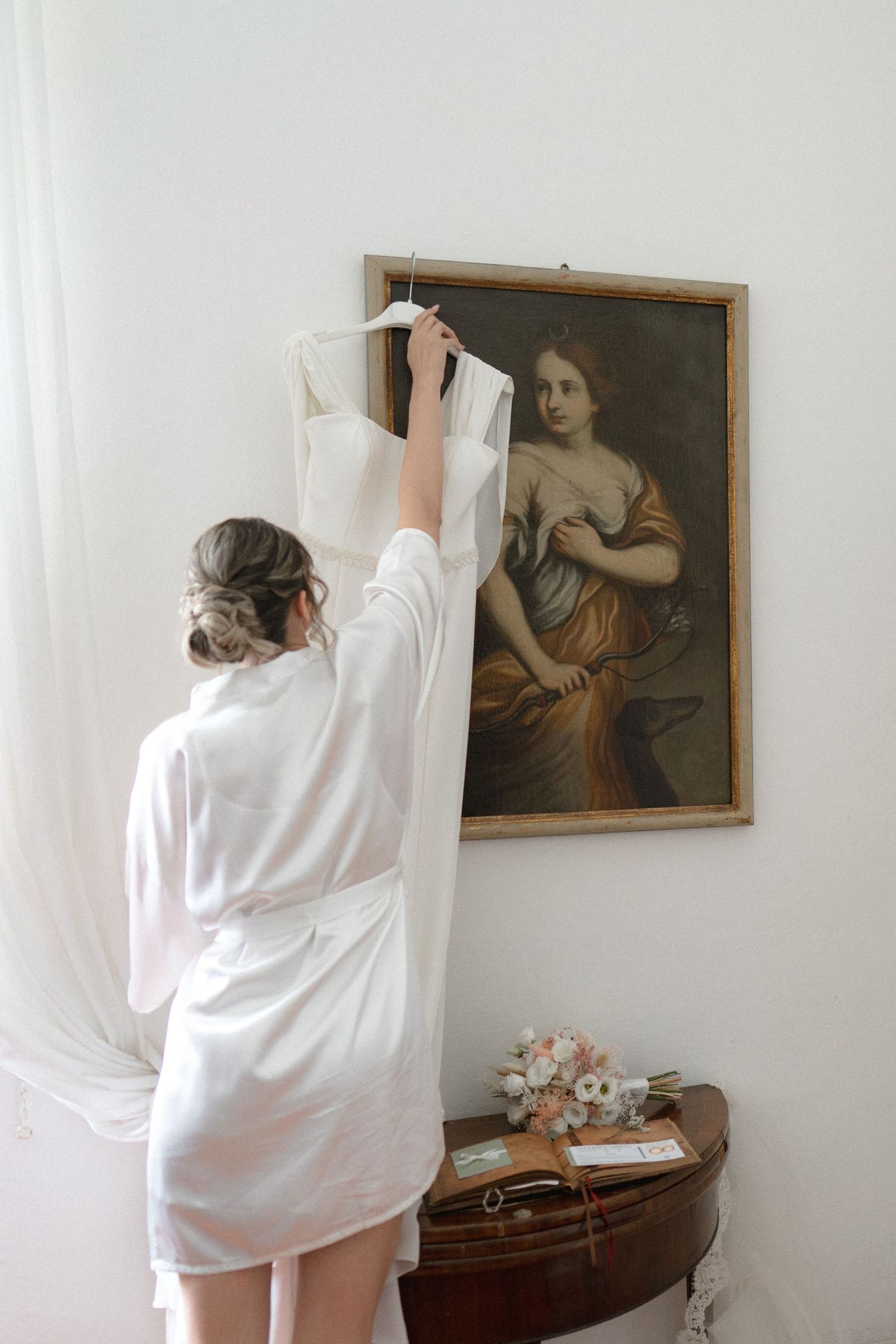 A sequence of photos shows someone in white fabric moving and posing in front of a vintage portrait on a wall.
