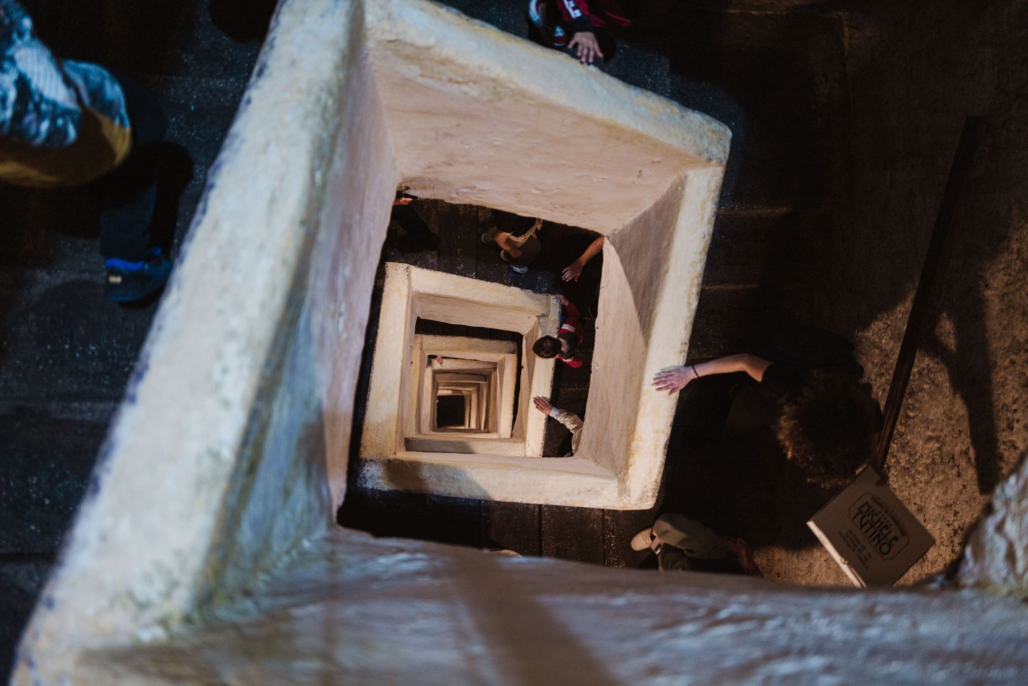 Looking down a spiral staircase creates a mesmerizing geometric pattern of white walls descending into darkness.