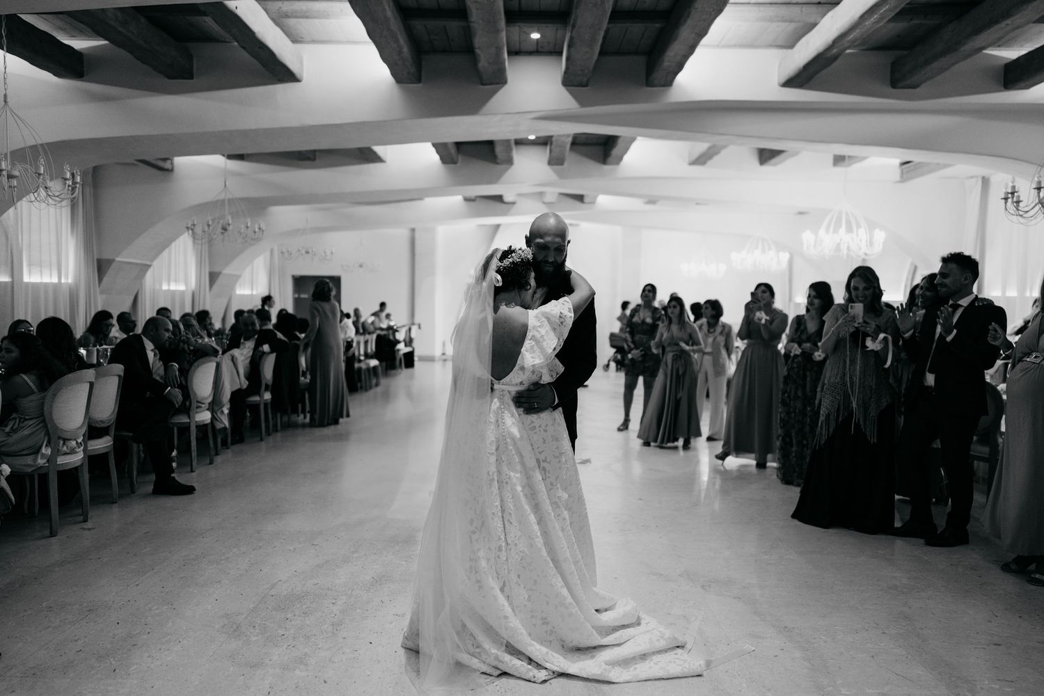 Black and white photograph of a wedding dance in a spacious reception venue.