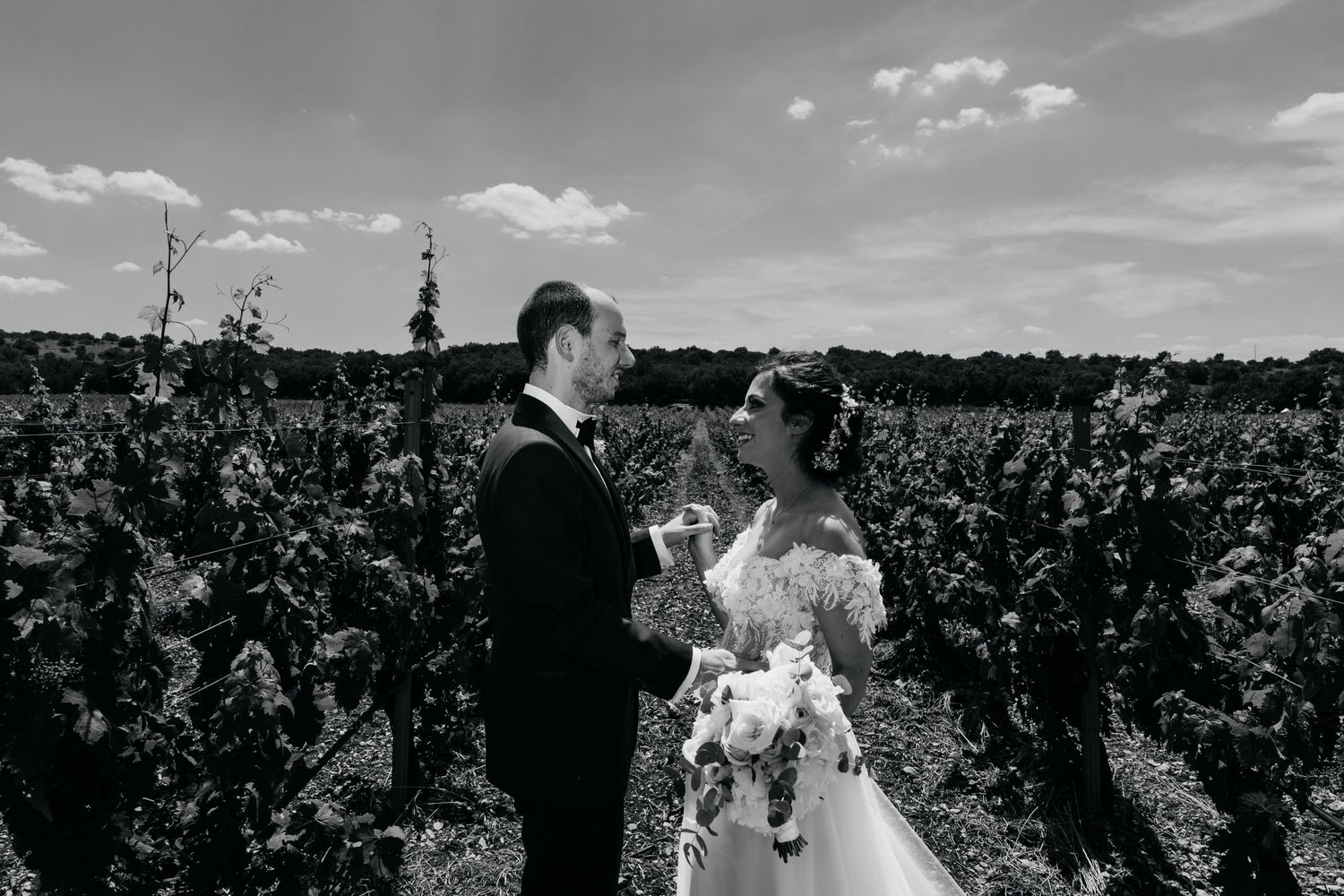 A romantic moment between newlyweds among vineyard rows on their wedding day.