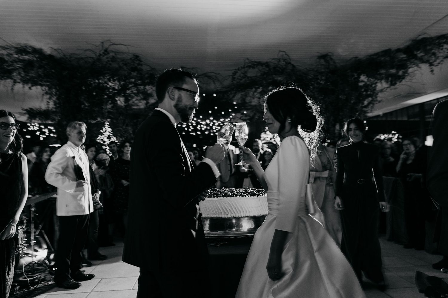 Bride and groom share a romantic first dance at an elegant evening wedding reception with guests watching.