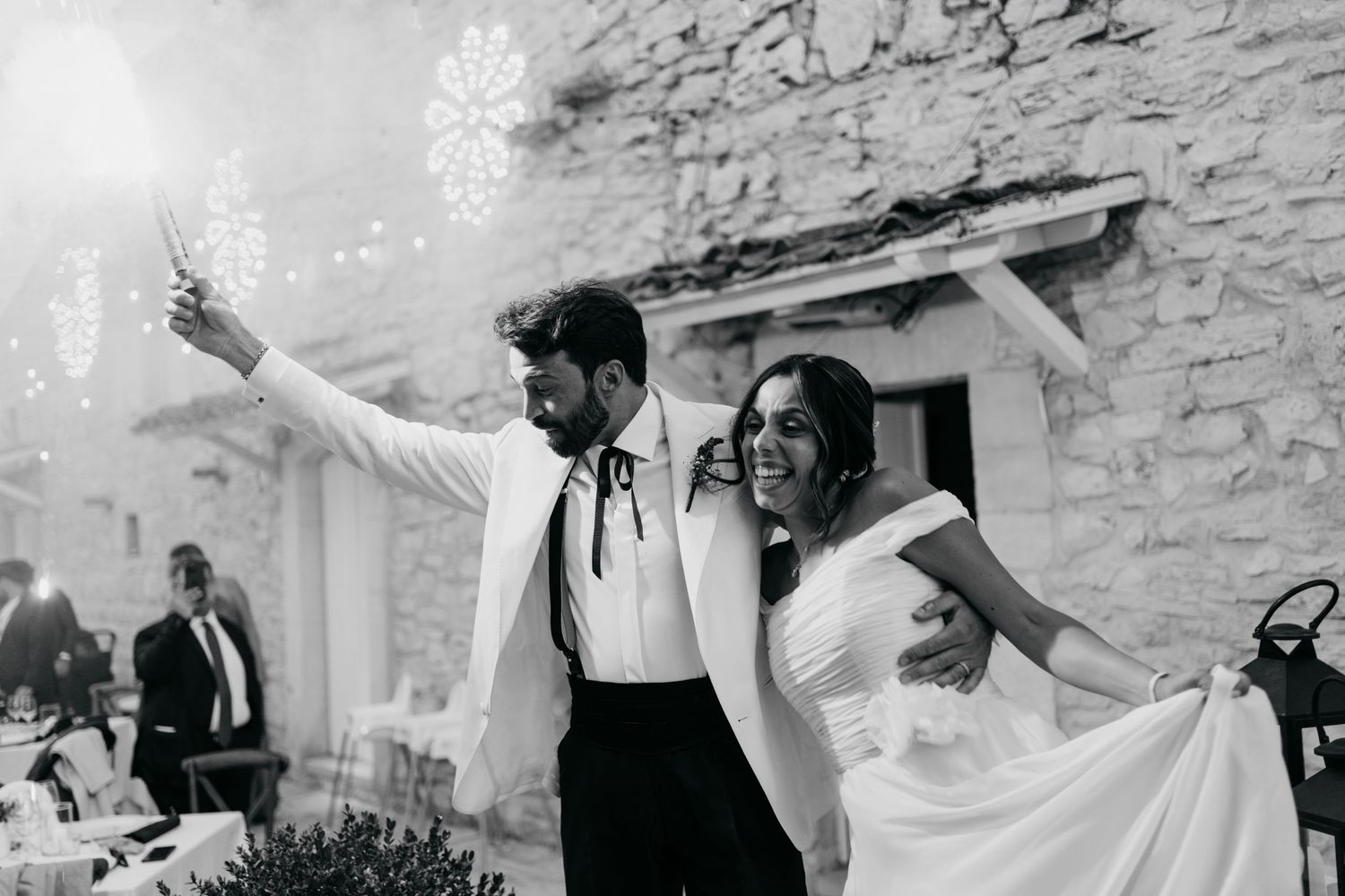 A joyous celebration with sparklers at a rustic stone venue during a wedding reception.