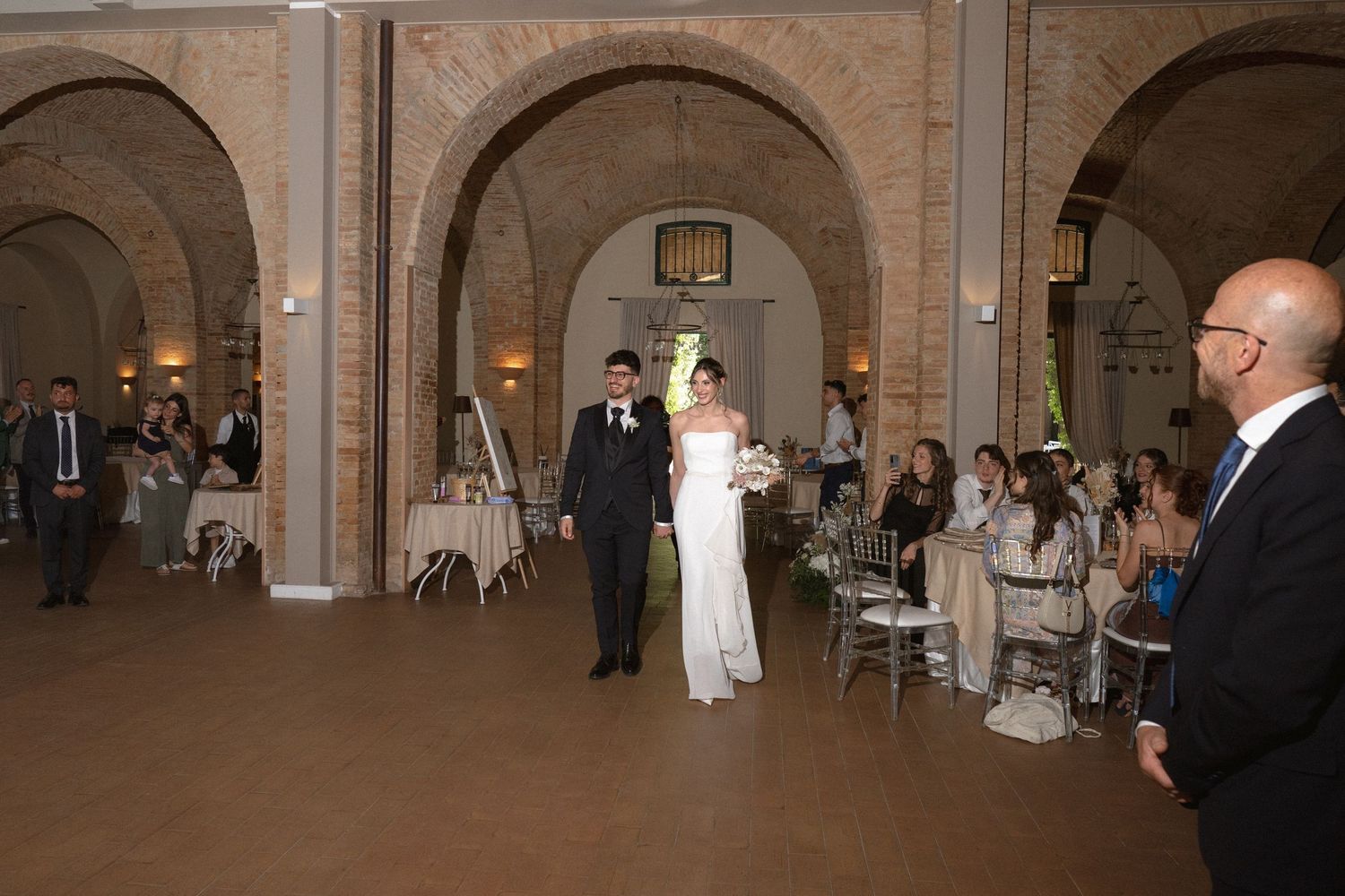 Wedding reception in grand stone archway venue with purple floral decor.