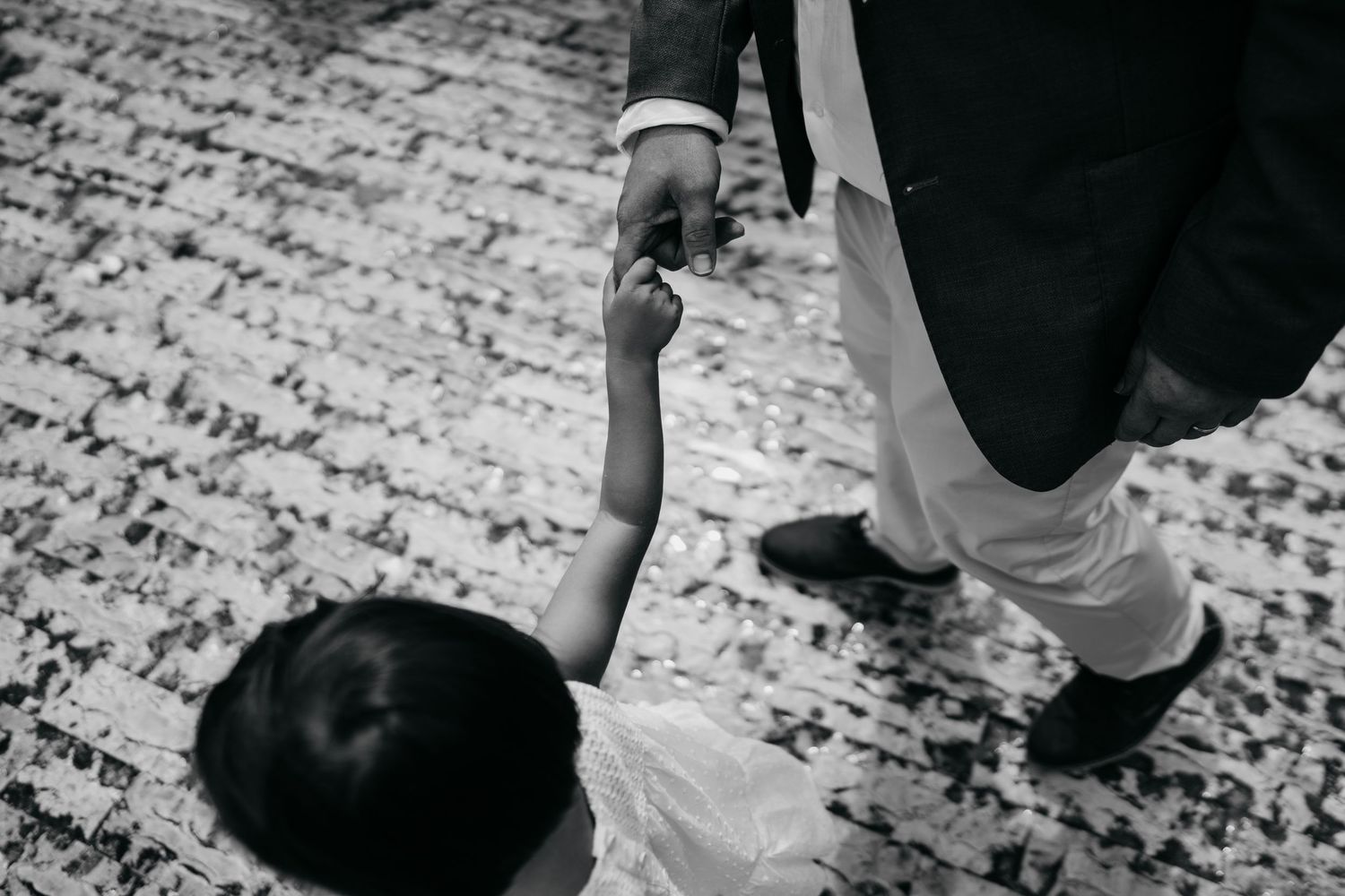 Black and white photo of people dancing on a patterned floor at a celebration.