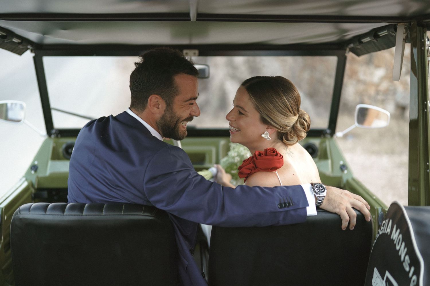 Couple shares a joyful moment while sitting in a vintage vehicle together.
