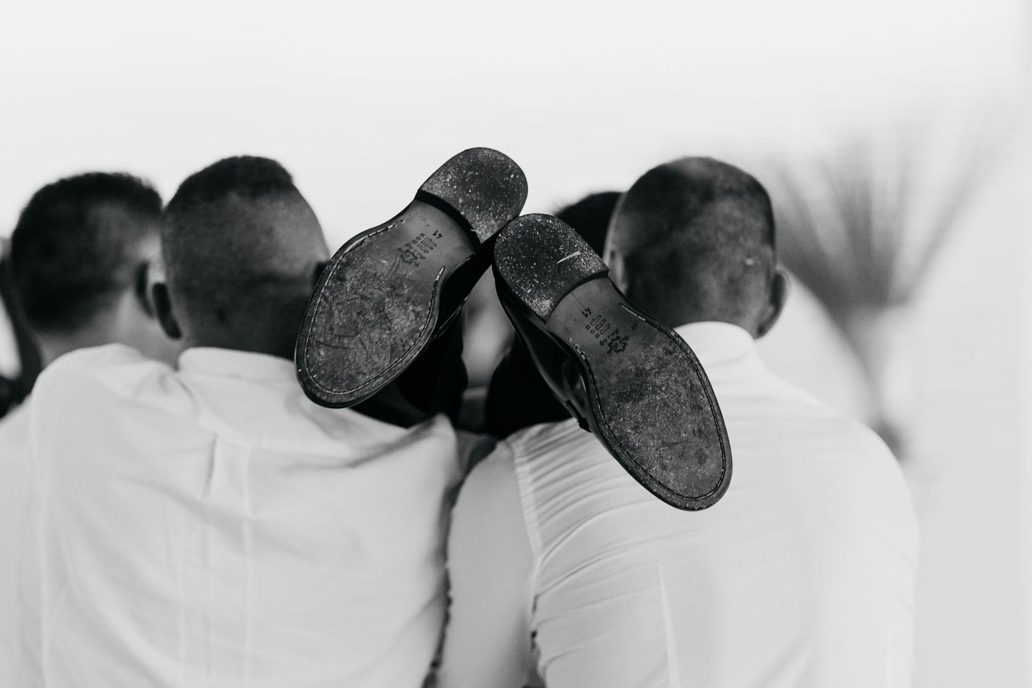 Black and white photo of groomsmen's shoes in a creative formation.