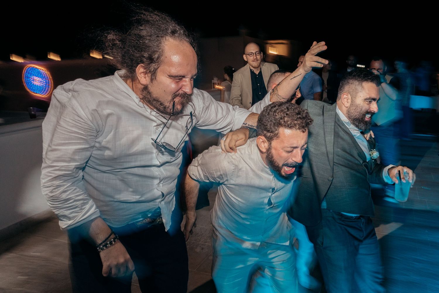 Energetic guests dancing and celebrating wildly at a nighttime wedding reception.