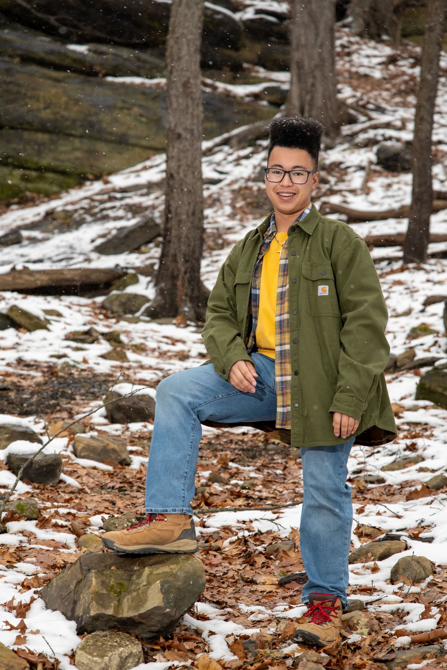 Winter hiking scene with snow patches and pine trees in a rugged mountain landscape.