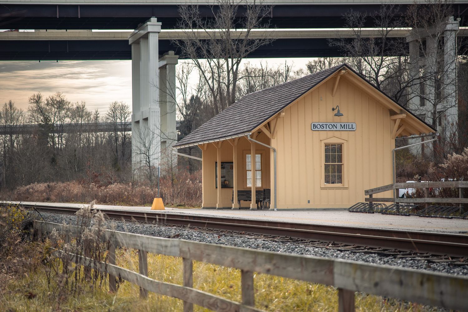 Yellow train station building with wooden platform and railroad tracks in winter scenery.